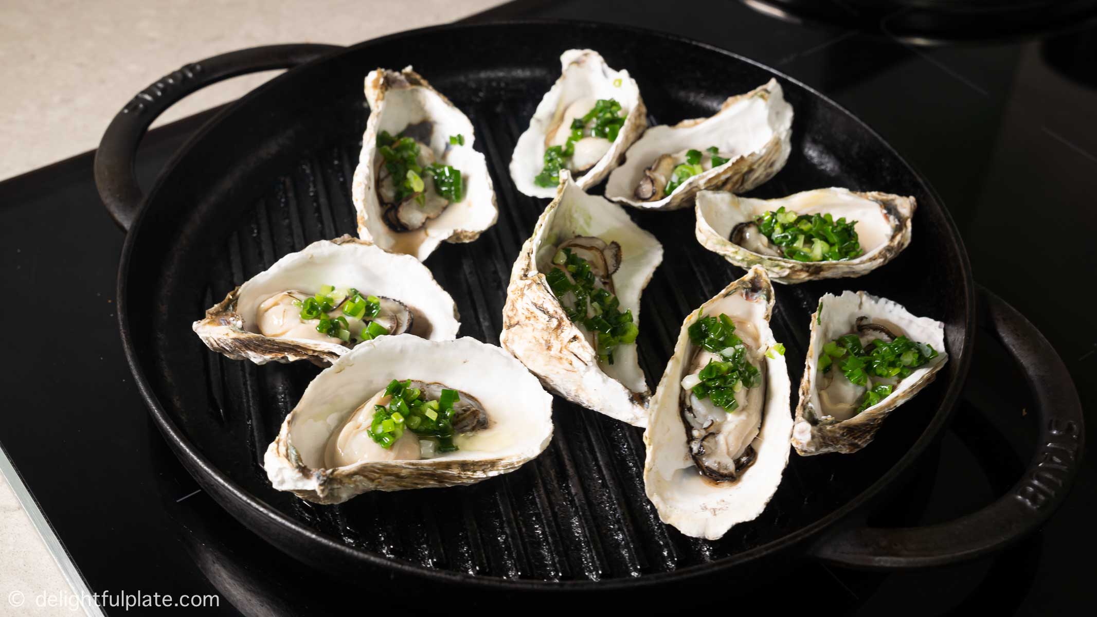 oysters on a grill pan, with scallion oil on top
