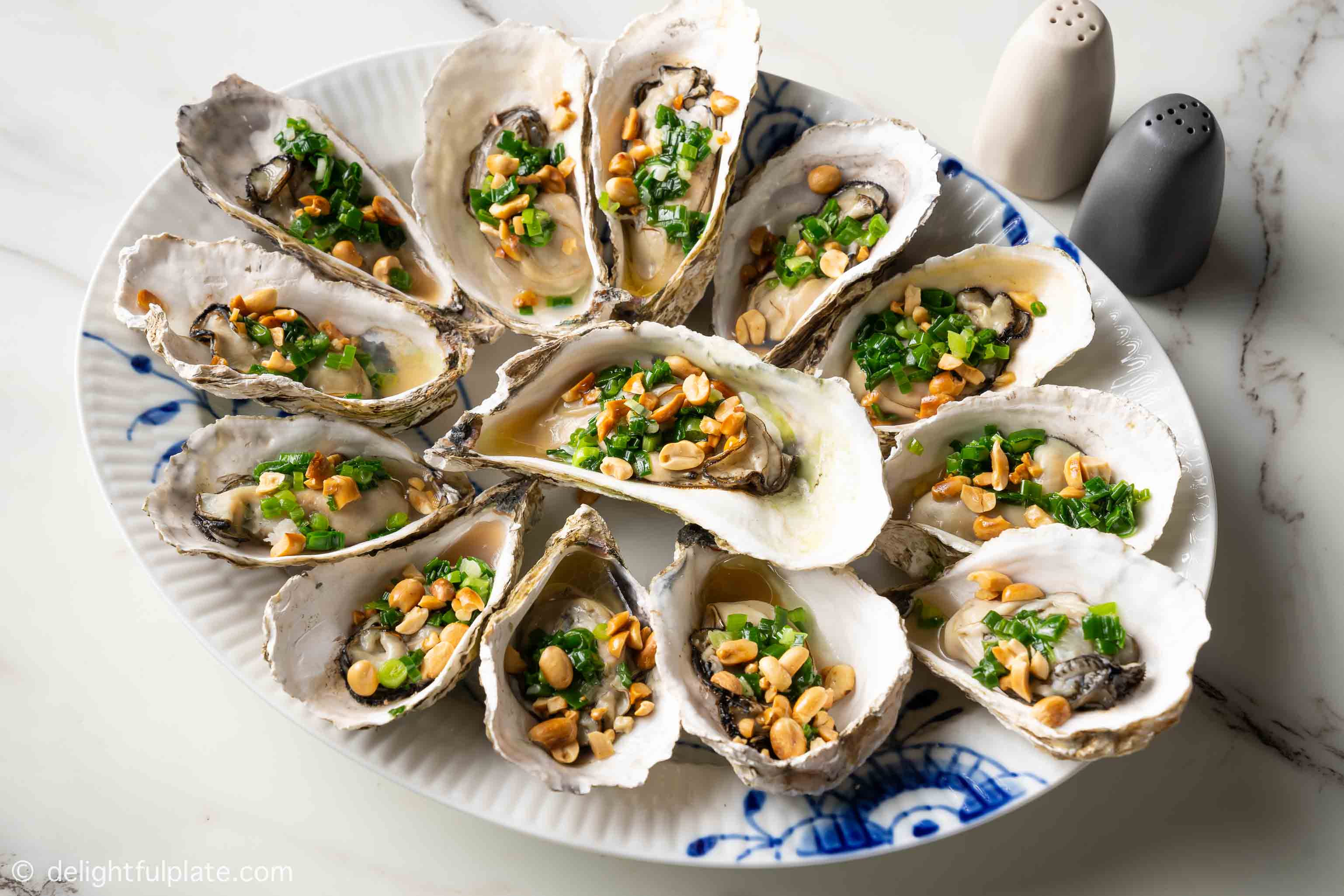 a plate of grilled oysters topped with scallion oil and roasted peanuts 