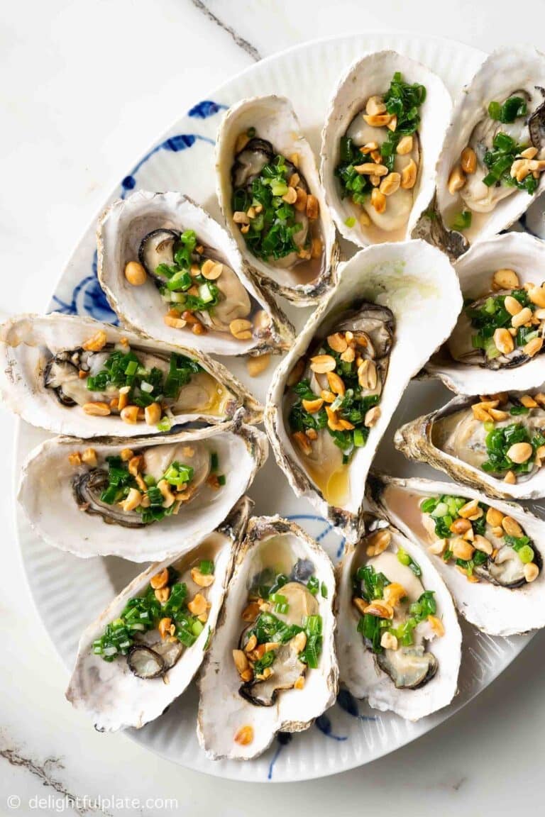 a plate of grilled oysters topped with scallion oil and roasted peanuts