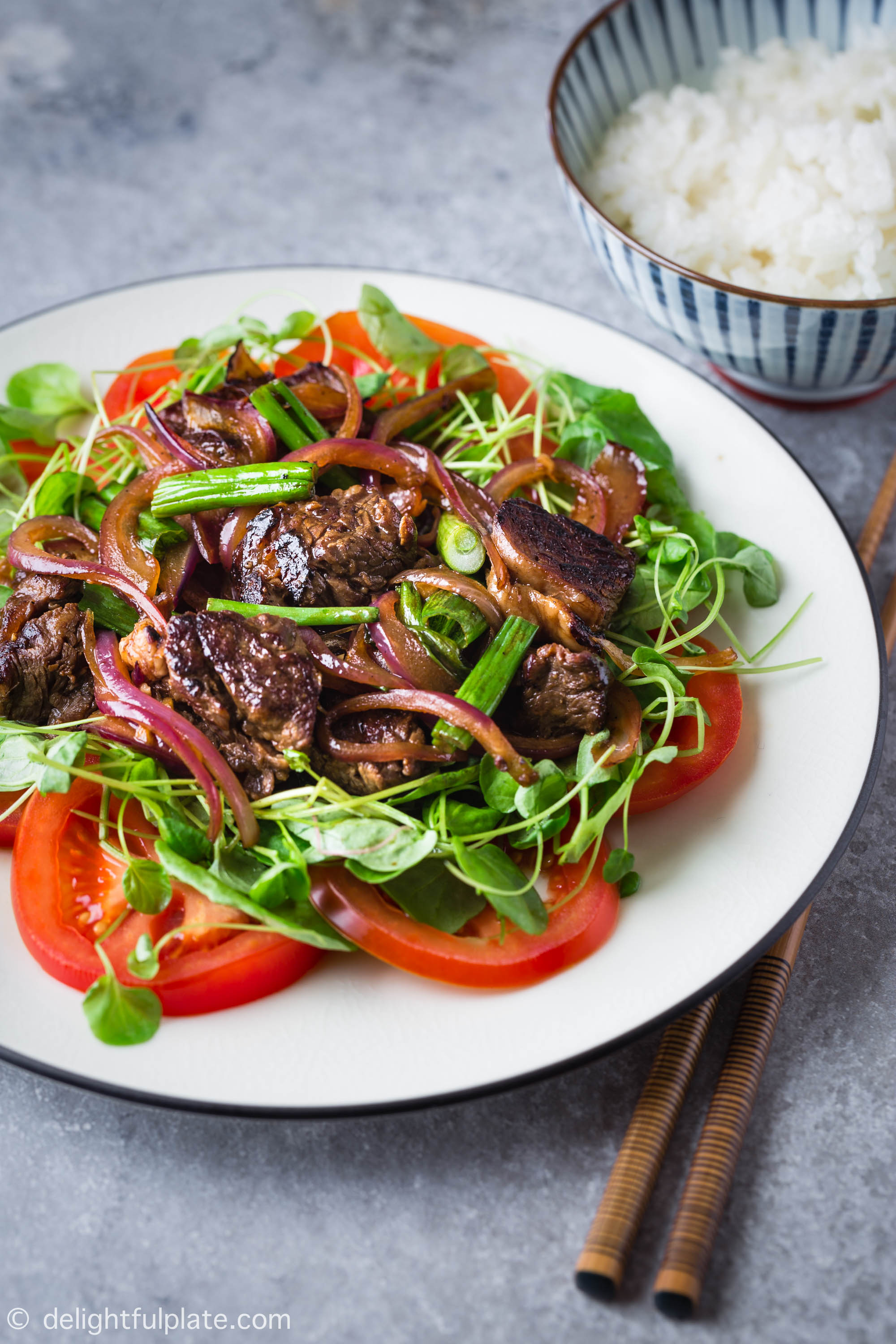 Vietnamese Shaking Beef (Bo Luc Lac) is an easy and delicious one-pan meal that is excellent for everyday meals as well as special occasions. This dish features tender and flavorful beef plated on a bed of green cress and fresh tomatoes.