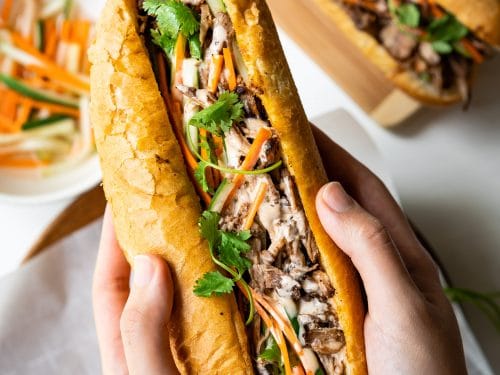 This Vietnamese Pulled Pork Banh Mi features crispy bread, tender and flavorful pork, crunchy pickled vegetables and yummy sriracha mayo sauce. With the help of a slow cooker, this banh mi sandwich recipe is super easy to make.