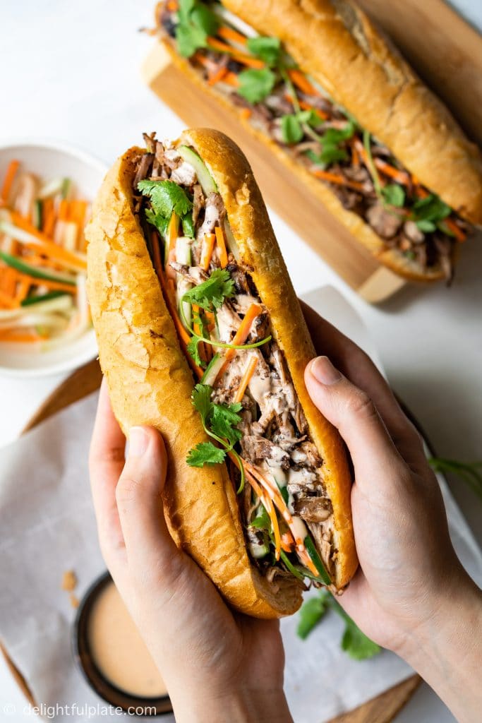 This Vietnamese Pulled Pork Banh Mi features crispy bread, tender and flavorful pork, crunchy pickled vegetables and yummy sriracha mayo sauce. With the help of a slow cooker, this banh mi sandwich recipe is super easy to make.