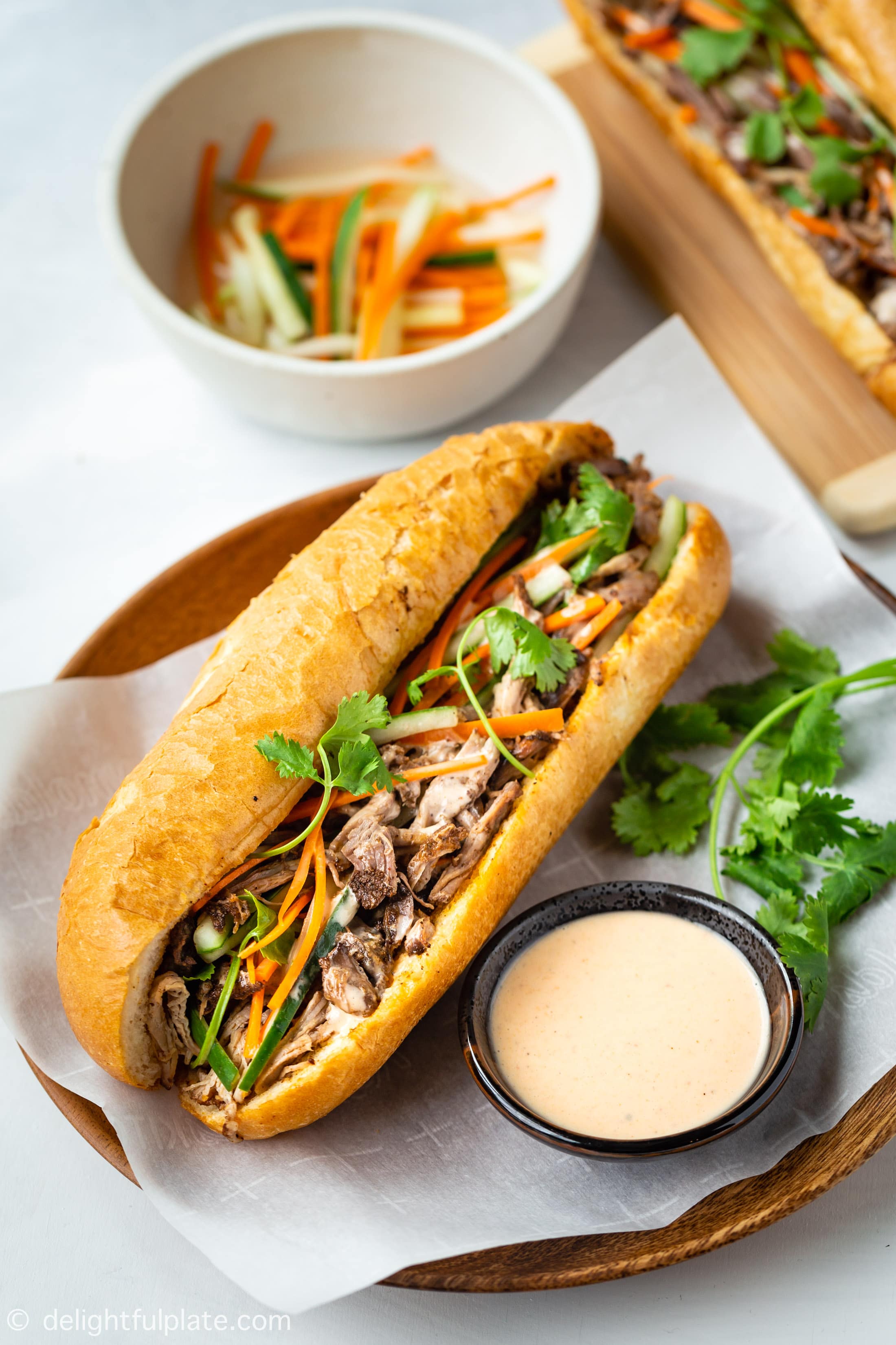 This pulled pork banh mi features Vietnamese baguette (banh mi) filled with tender and flavorful pulled pork, pickled vegetables, and tasty sriracha mayo sauce. With a slow cooker to cook the pulled pork, this delicious banh mi recipe cannot be easier to make.