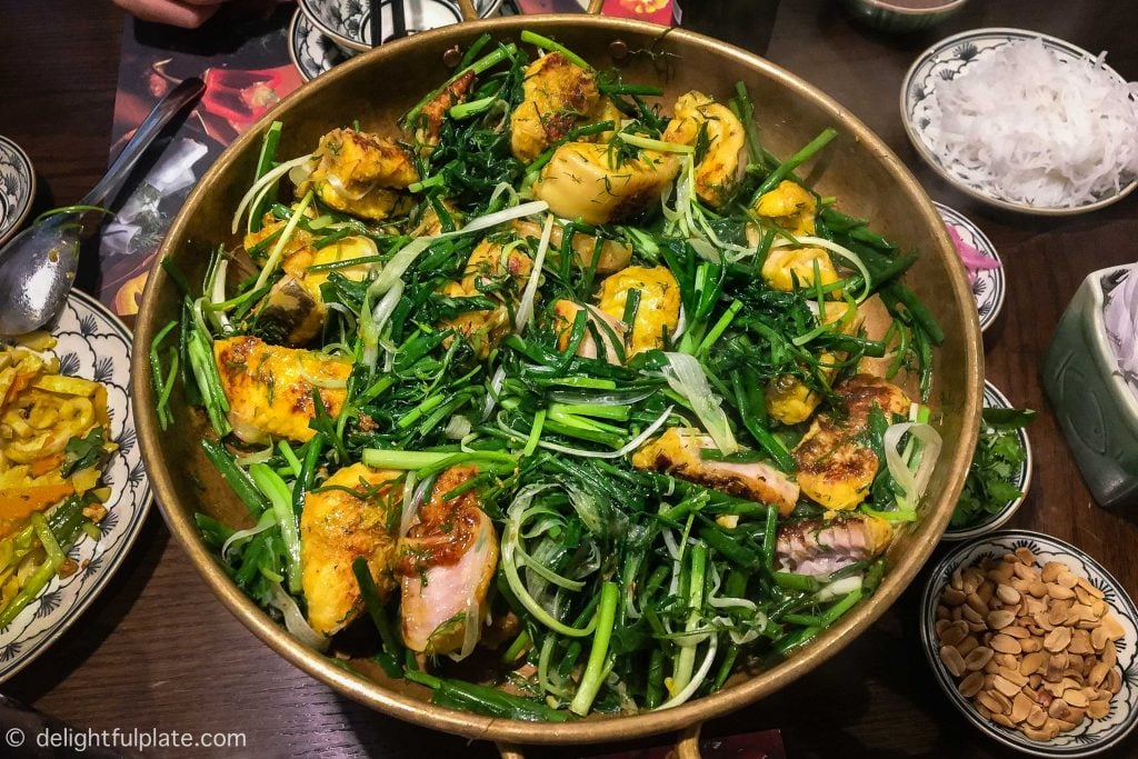 A pan of Cha Ca Hanoi with fish chunks, spring onion and dill