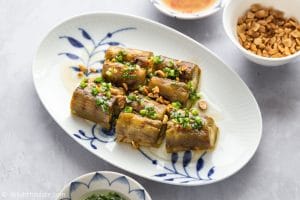 Vietnamese Whole Grilled Eggplant are topped with scallion oil, roasted peanuts and fish sauce dressing.