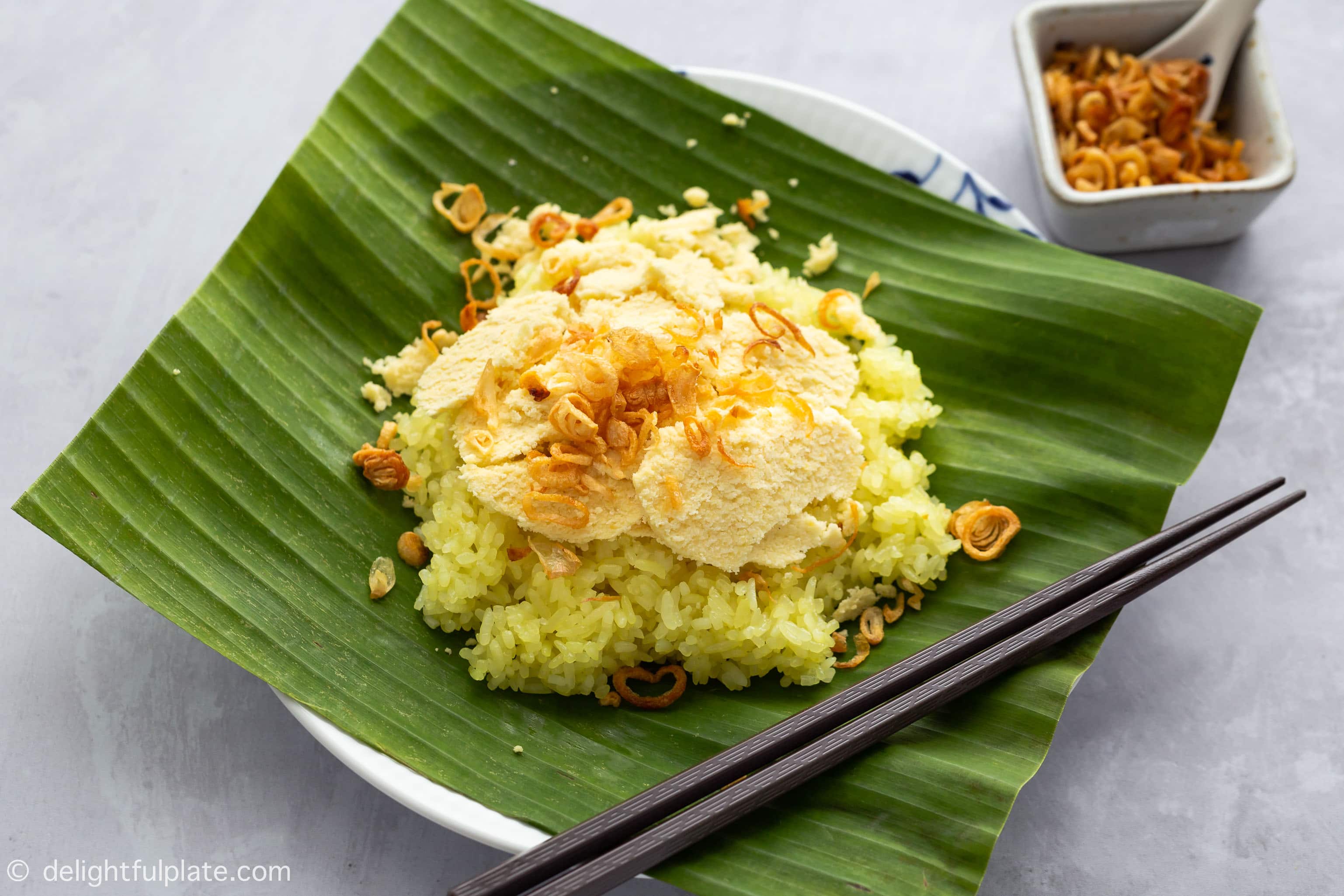 A plate of Xoi Xeo Hanoi, with Vietnamese steamed sticky rice, slices of mung bean and fried shallots.