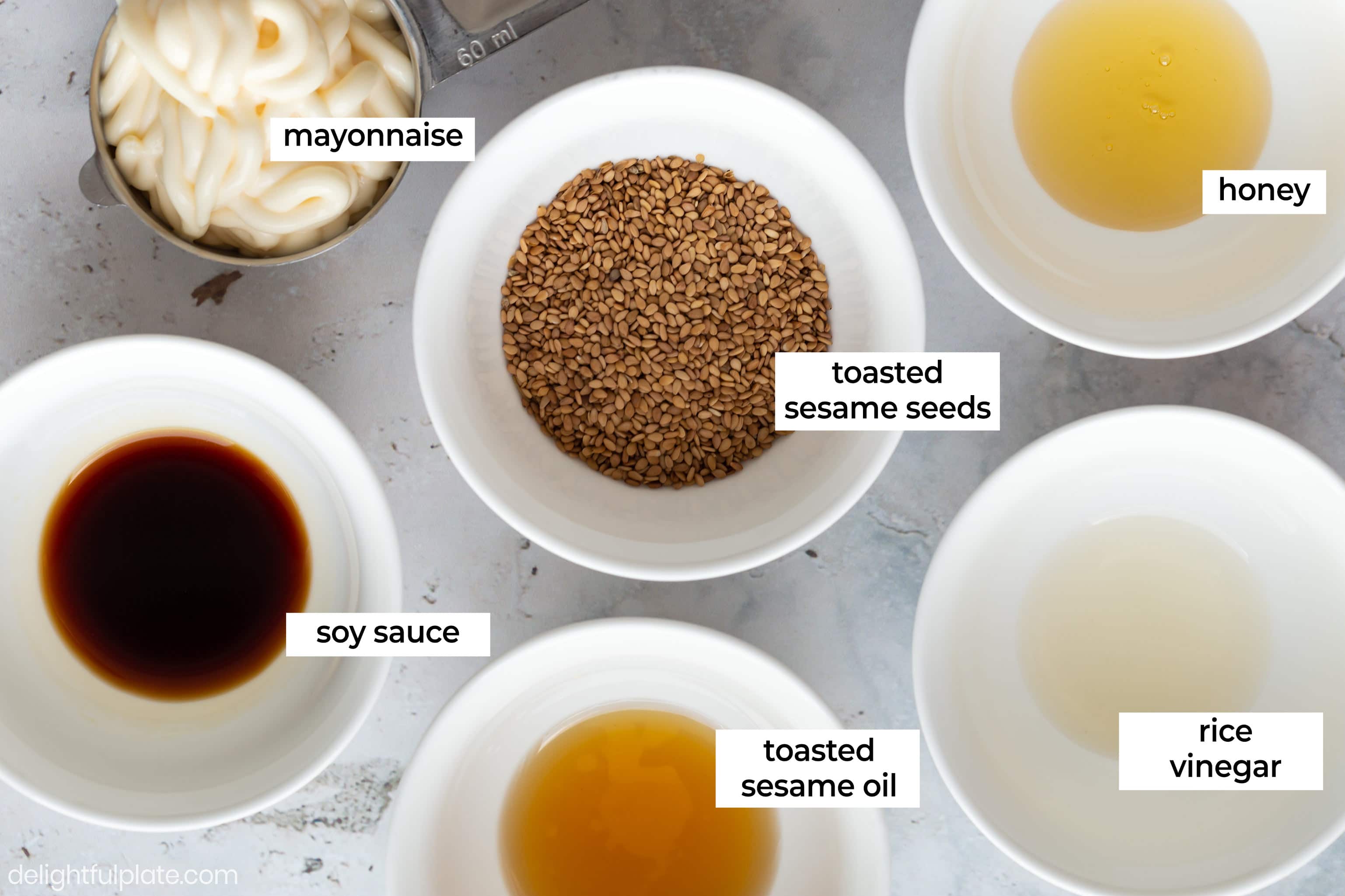 small bowls with ingredients for sesame dressing: mayonnaise, sesame seeds, honey, soy sauce, sesame oil and rice vinegar