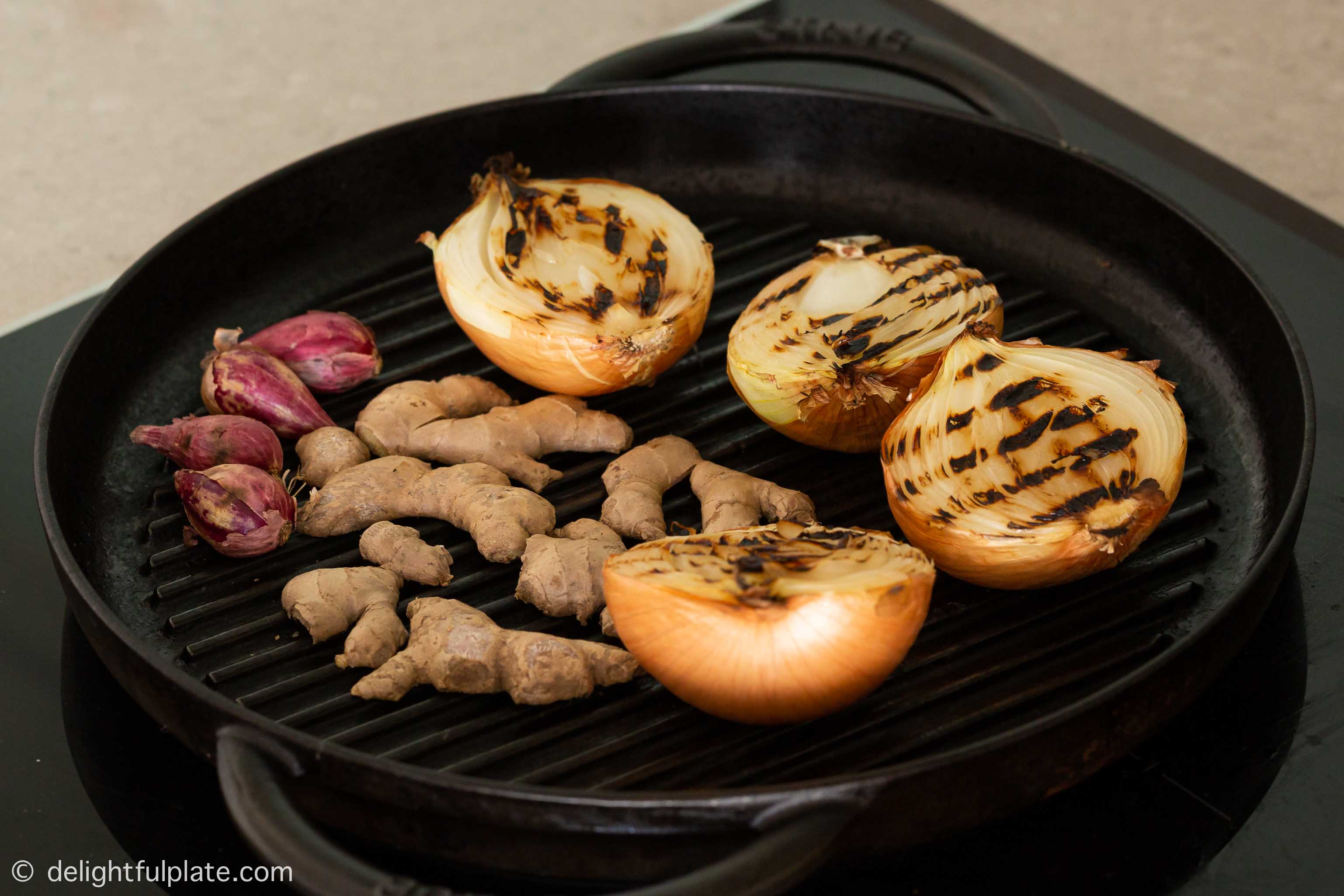 Zwiebeln, Ingwer und Schalotten in einer Grillpfanne rösten