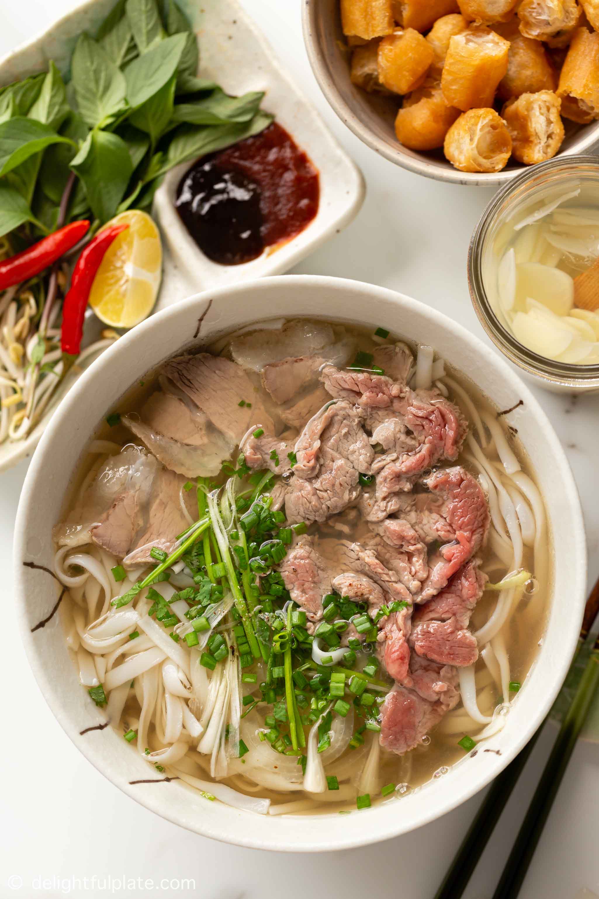 a bowl of Vietnamese pho noodle soup with well done beef and rare beef toppings.