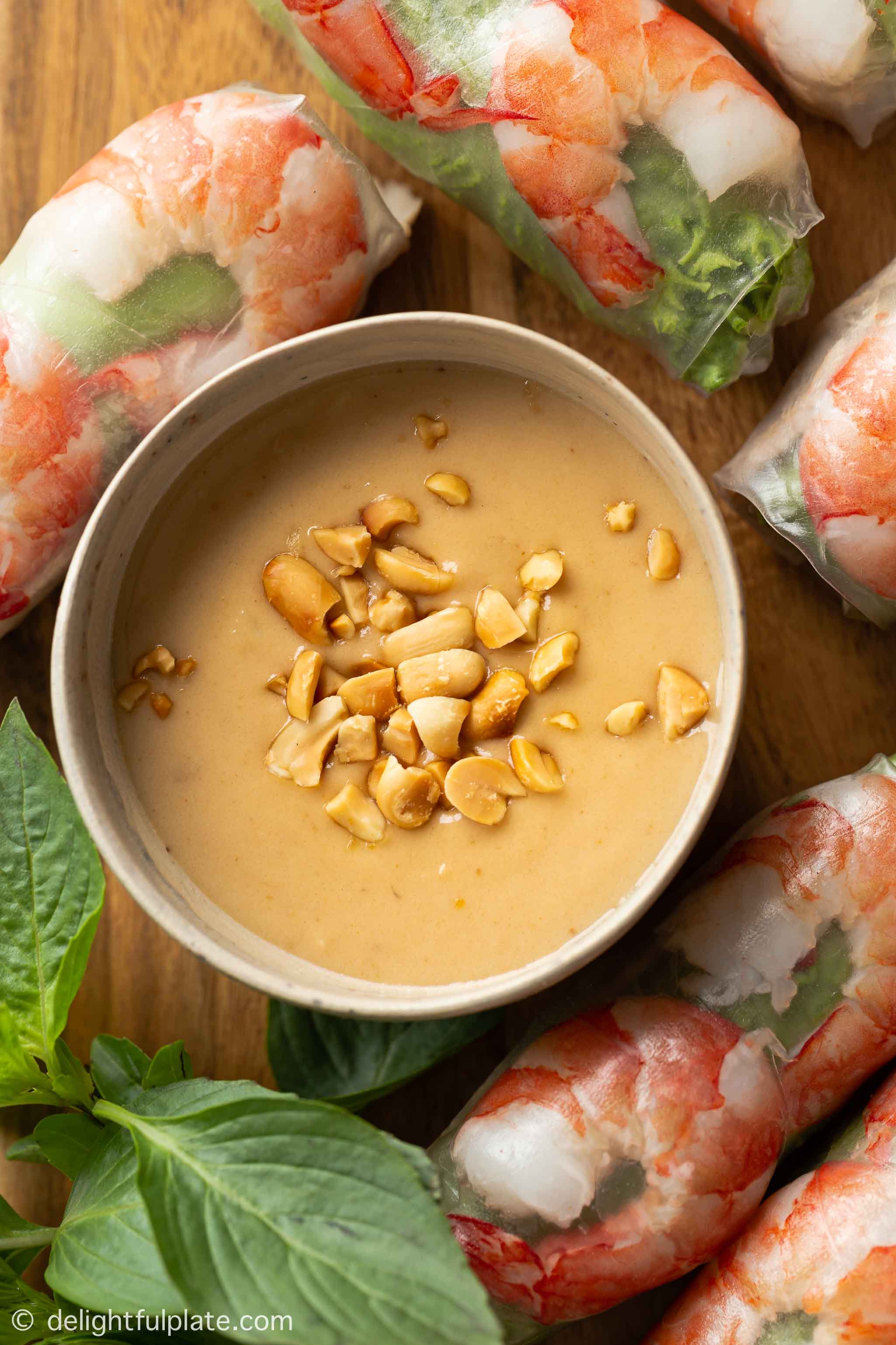 a bowl with peanut dipping sauce on a tray of Vietnamese fresh spring rolls