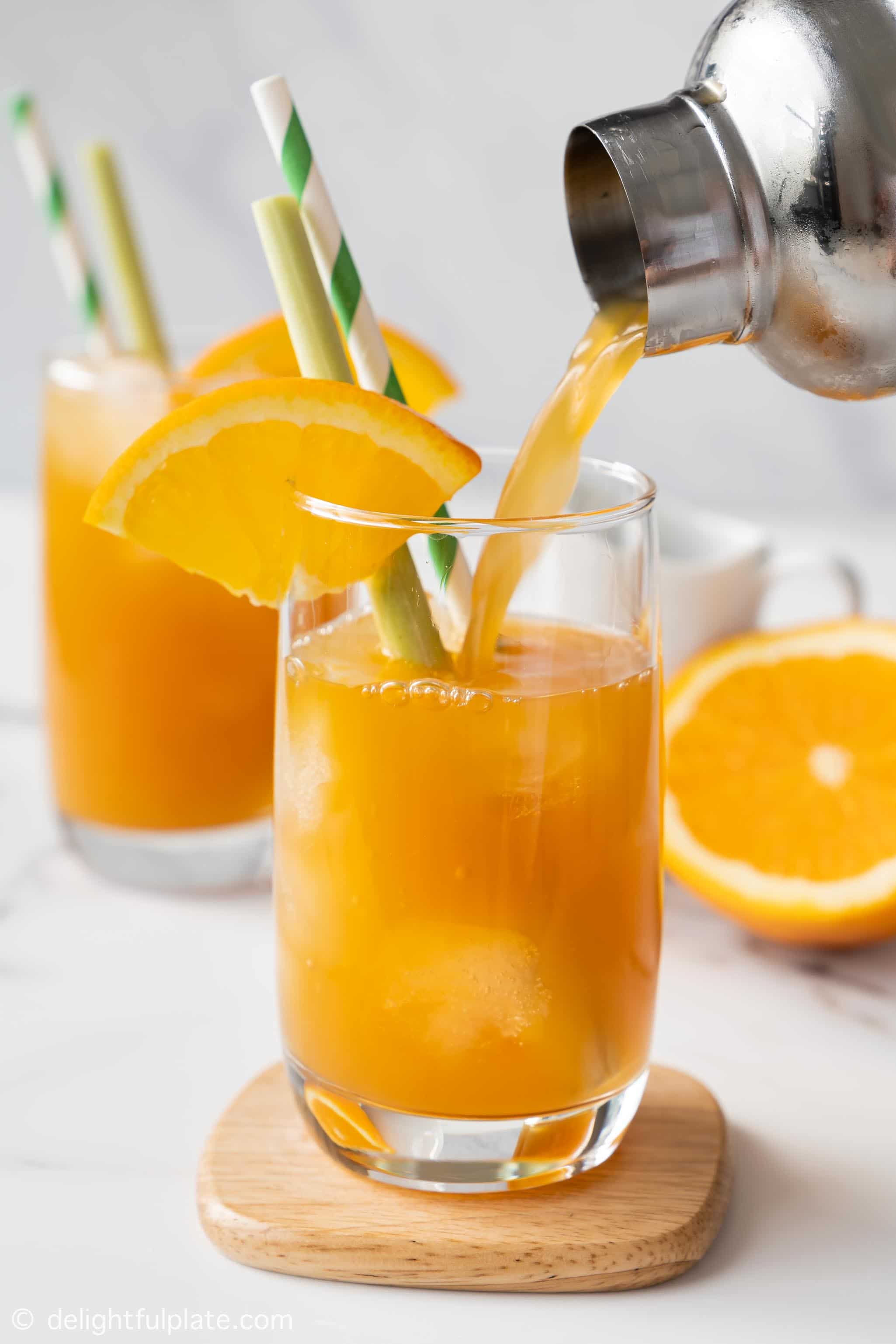 pouring ginger orange tea into a glass filled with ice