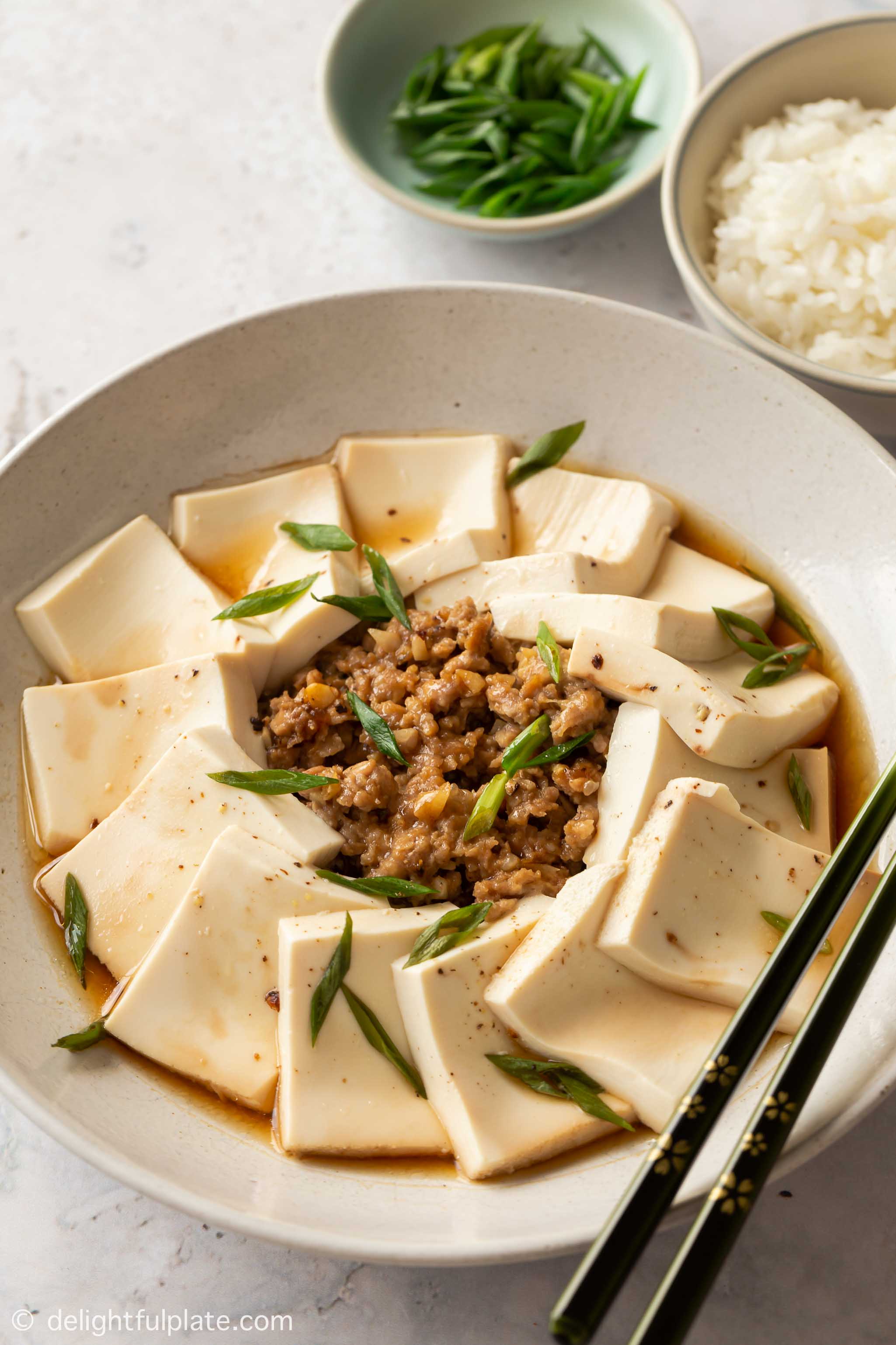 a plate of steamed tofu and ground pork, served with rice on the side