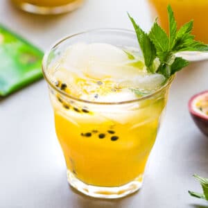 a glass of passion fruit iced tea, garnished with a sprig of mint
