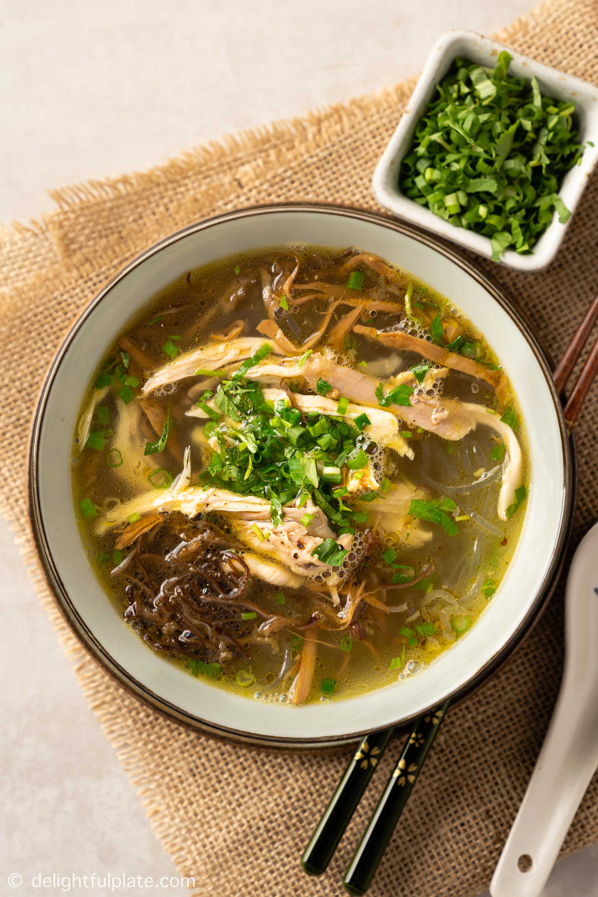 a bowl of chicken glass noodle soup with bamboo shoots