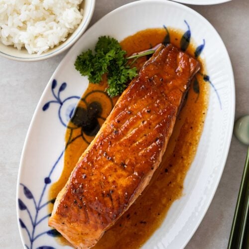 a glazed salmon fillet on a serving plate, accompanied with steamed rice