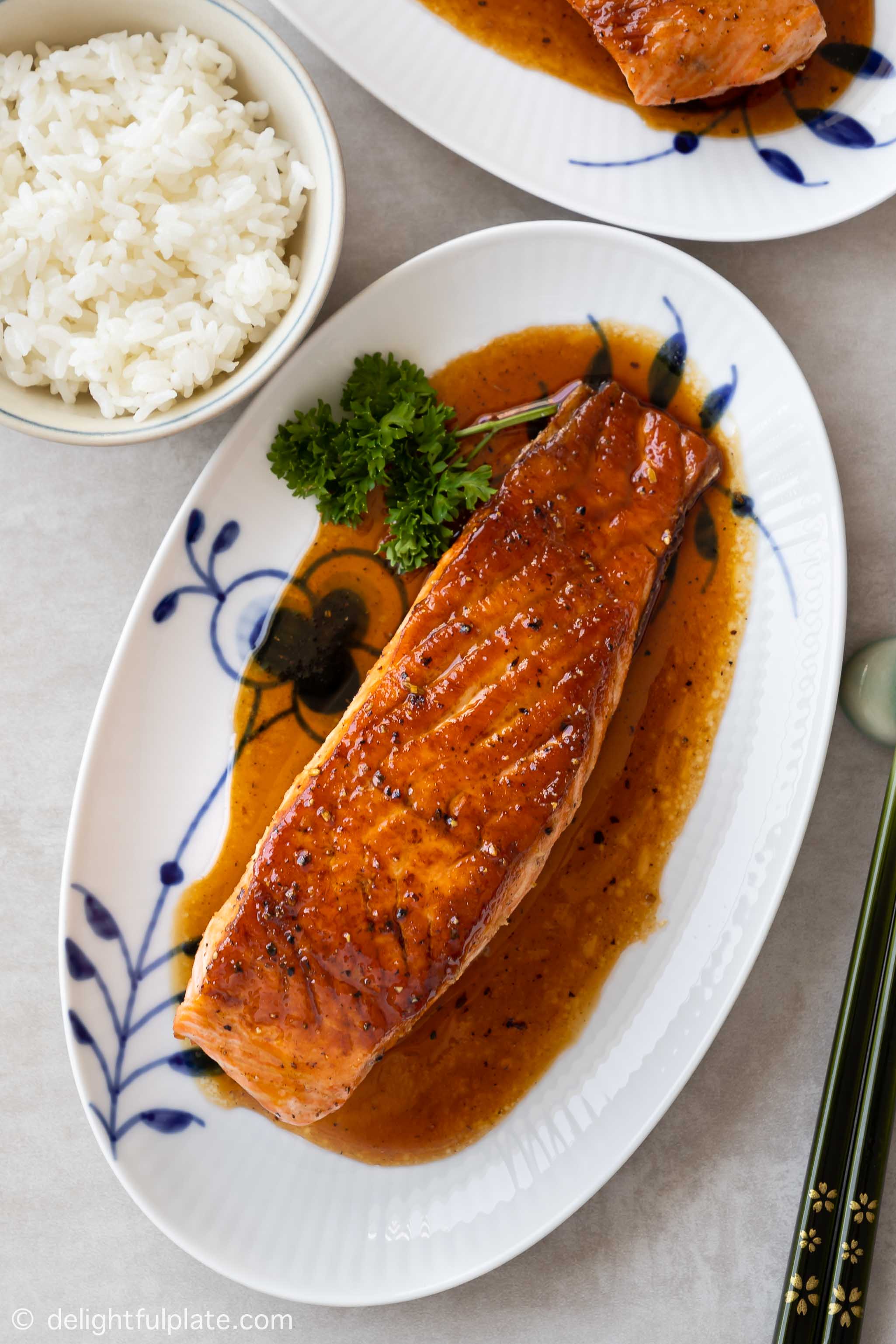 a glazed salmon fillet on a serving plate, accompanied with steamed rice