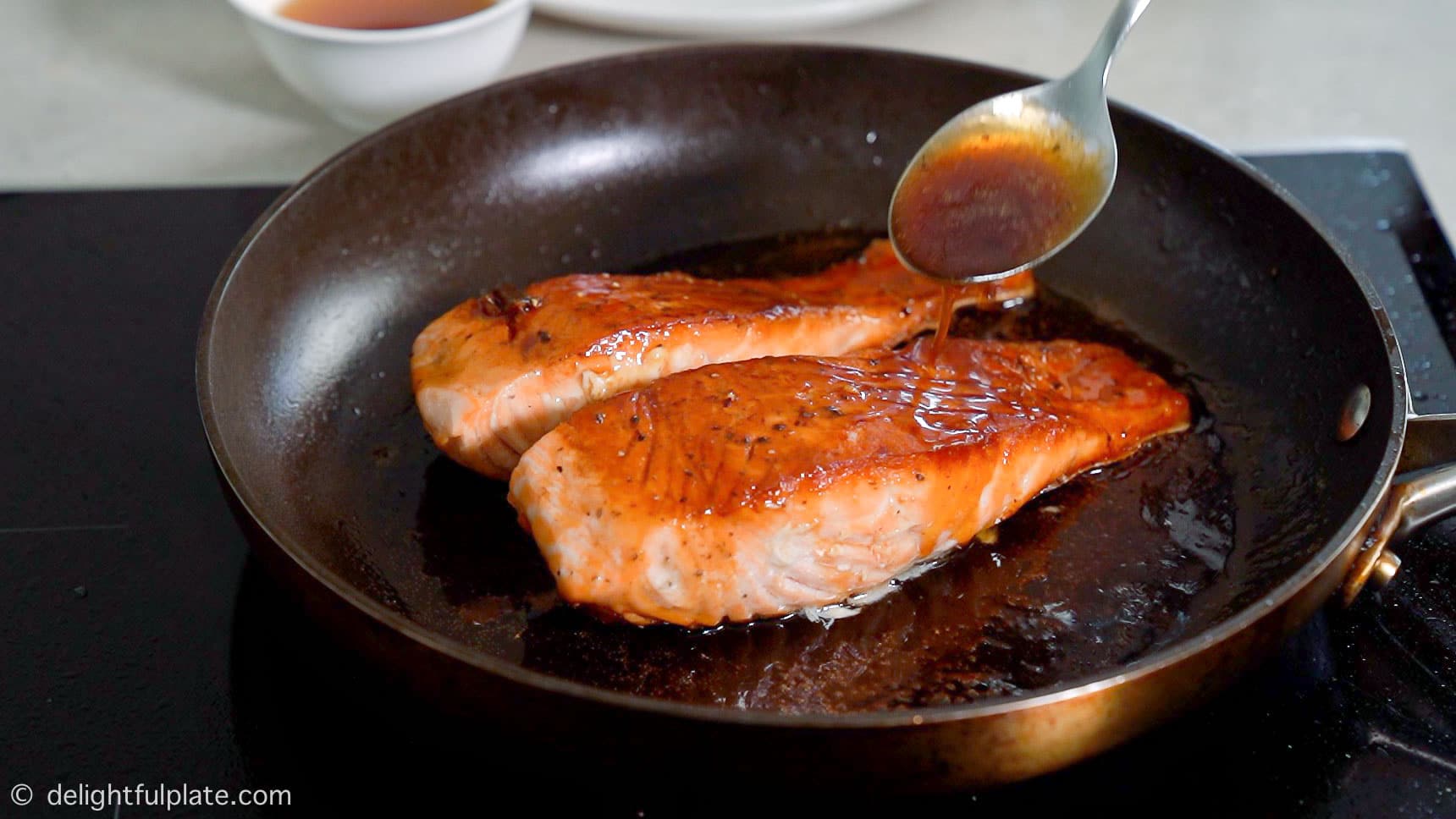 spooning the glaze over the salmon