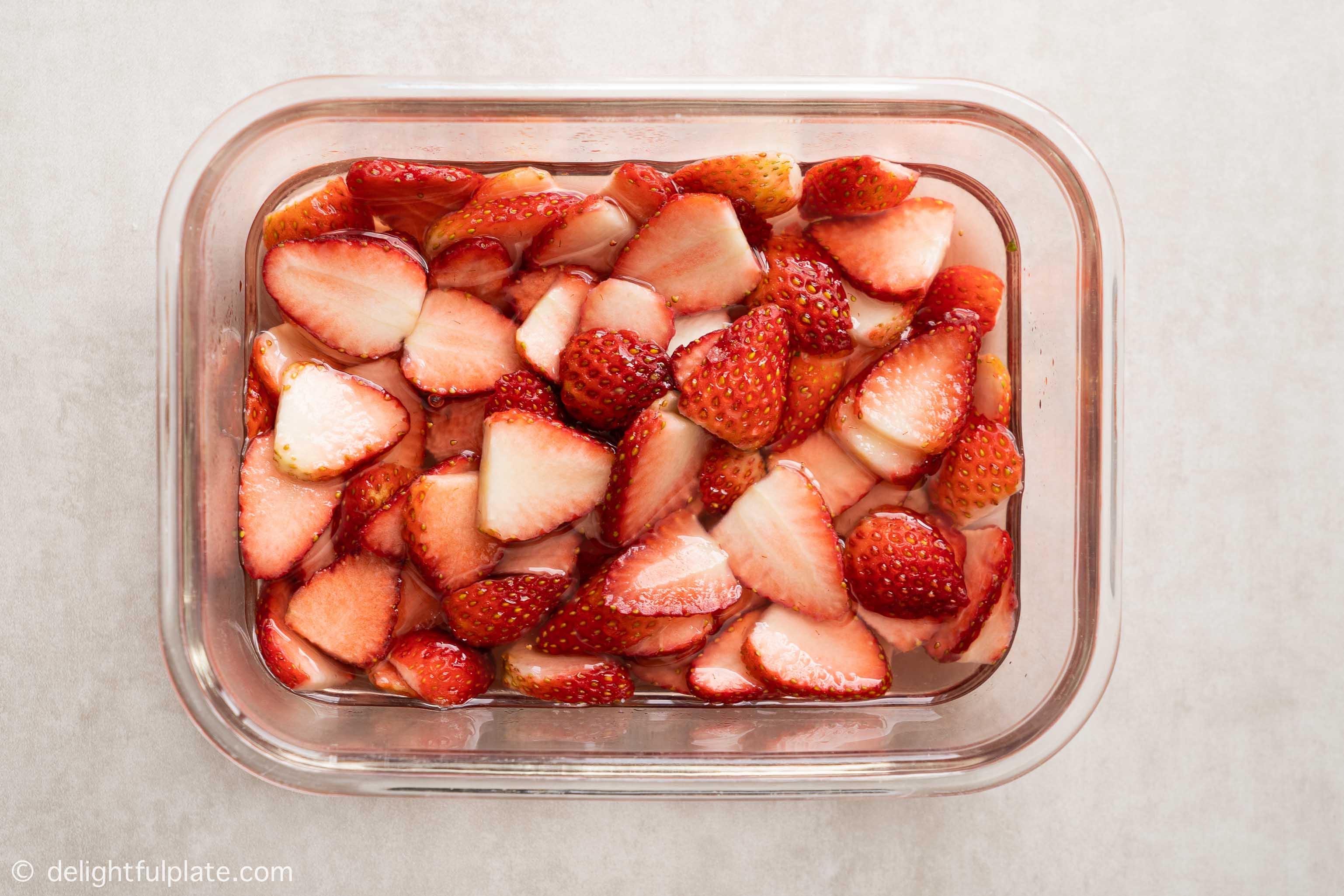 strawberry slices marinated in sugar in a container