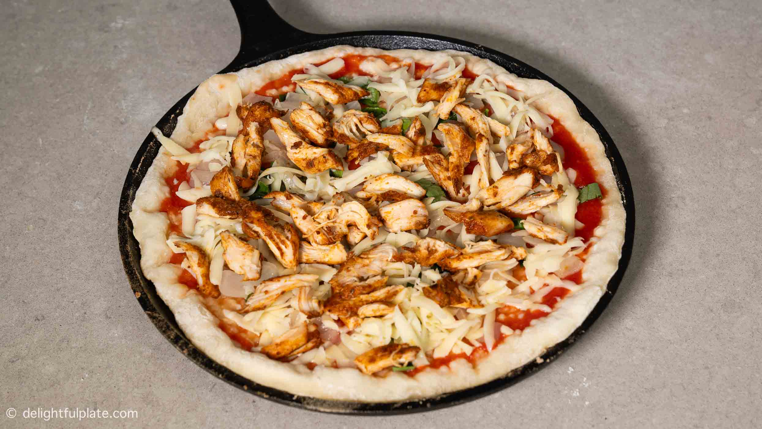 adding shredded chicken on the pizza.