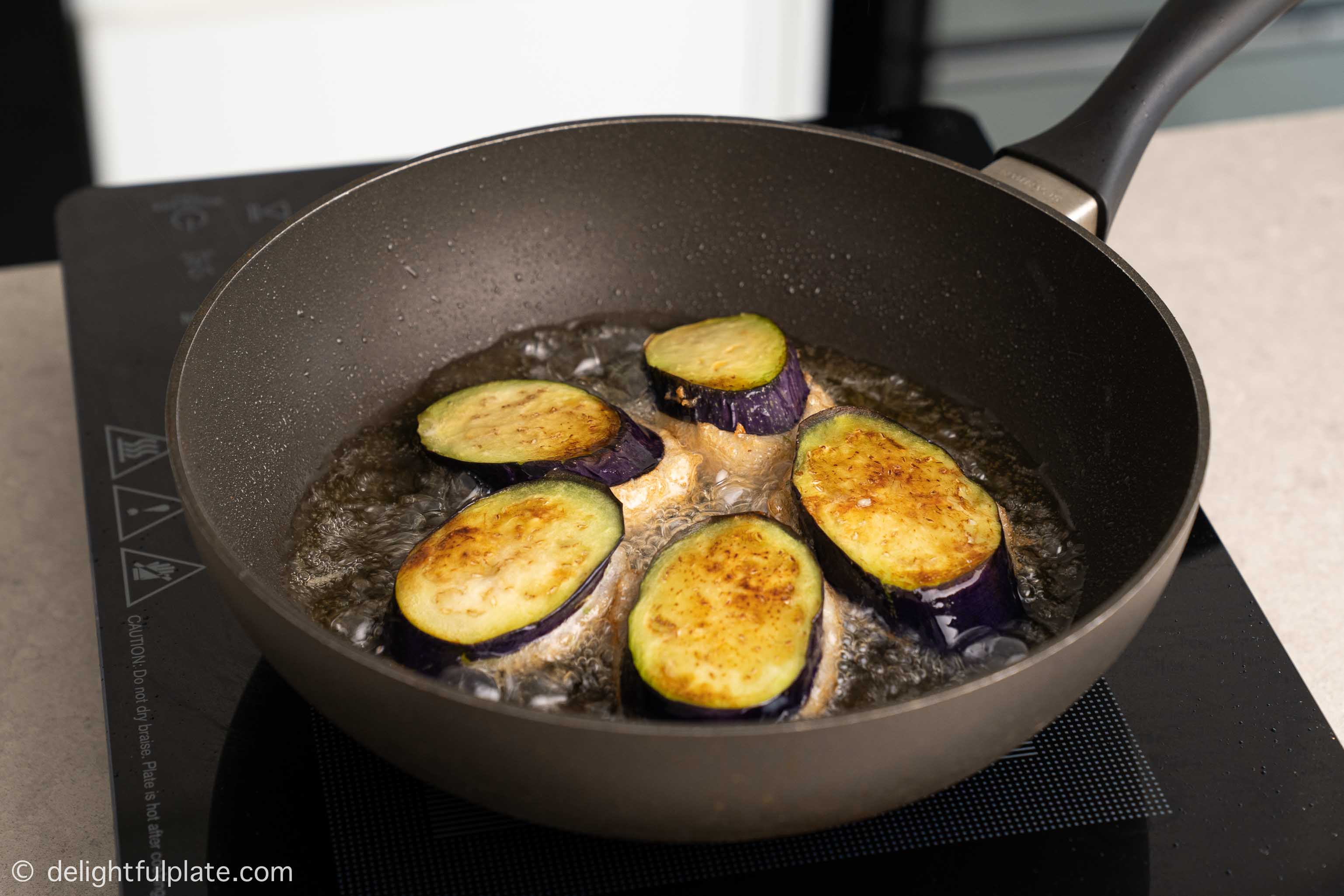 Frying stuffed eggplants in a pan