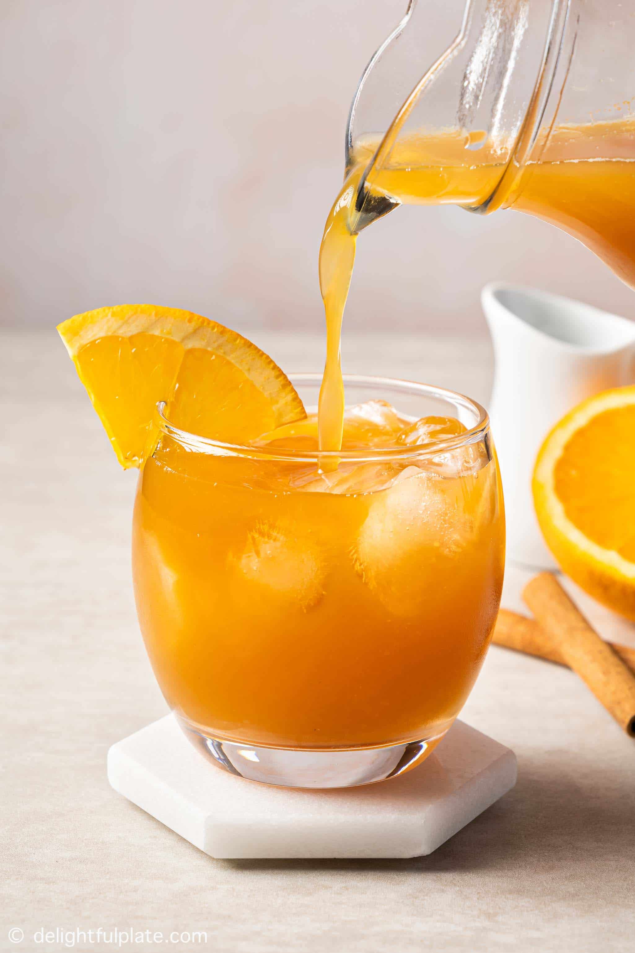 pouring orange cinnamon tea into a glass