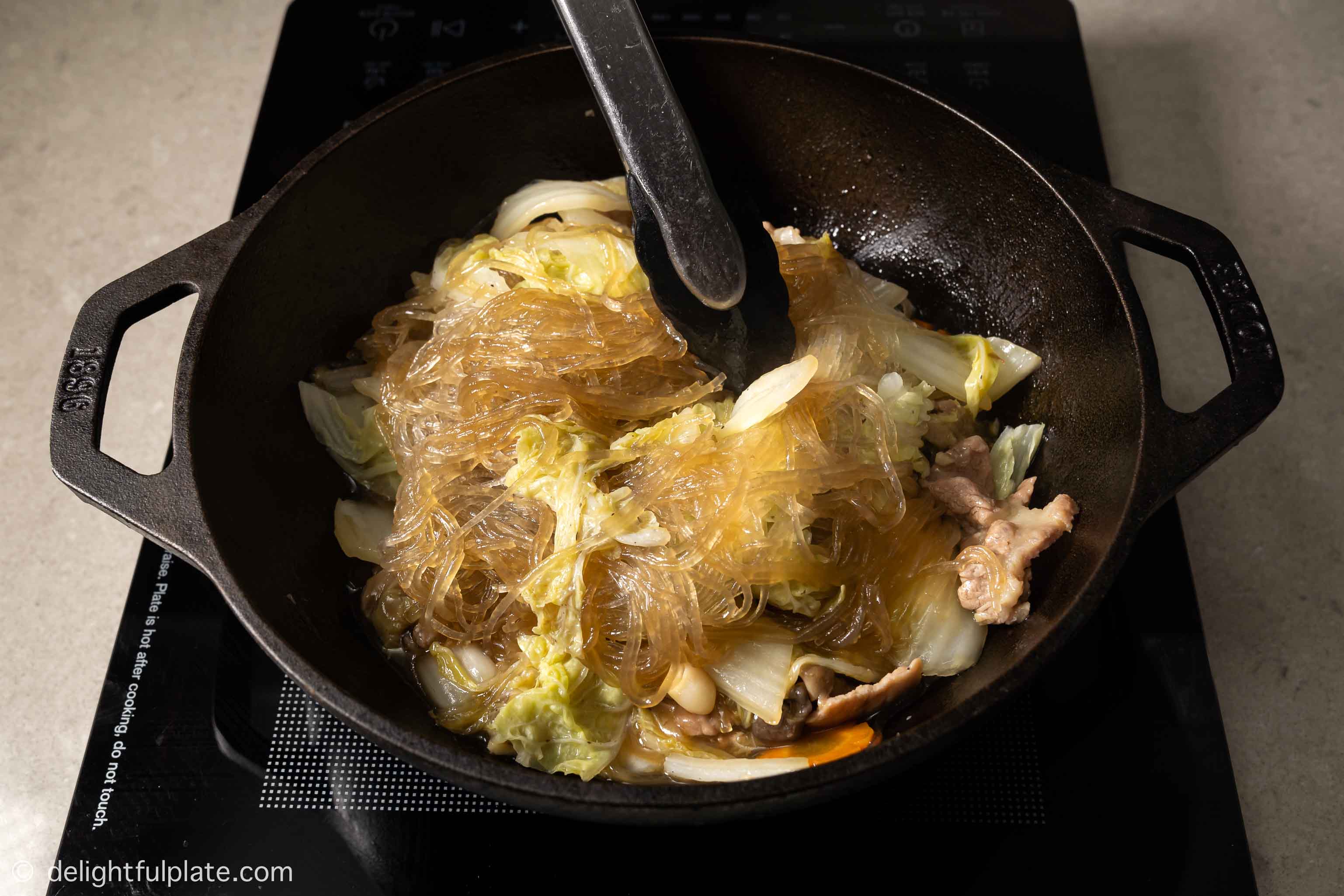 mixing the noodles with pork and cabbage