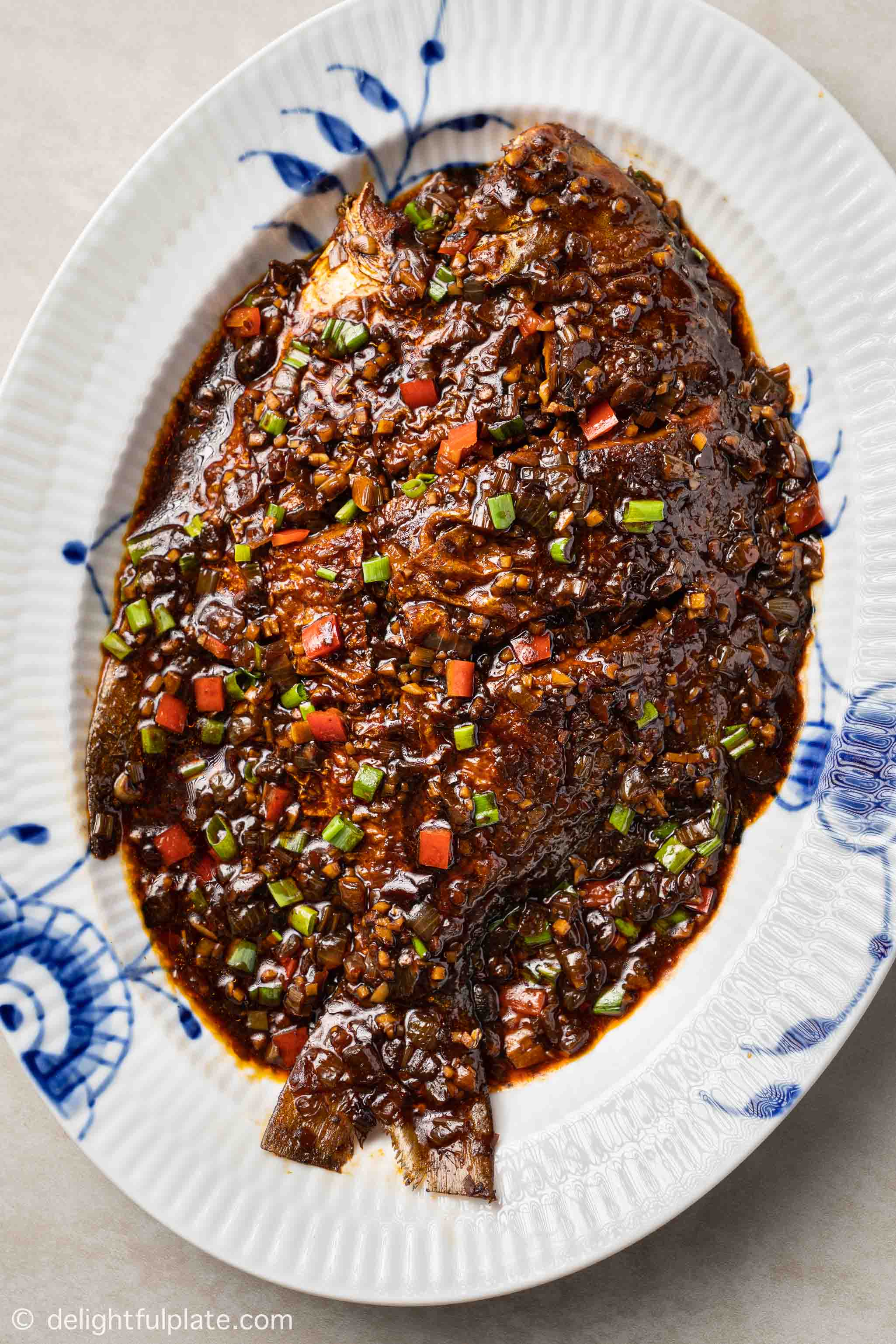 a braised whole fish in Lao Gan Ma sauce on a serving plate