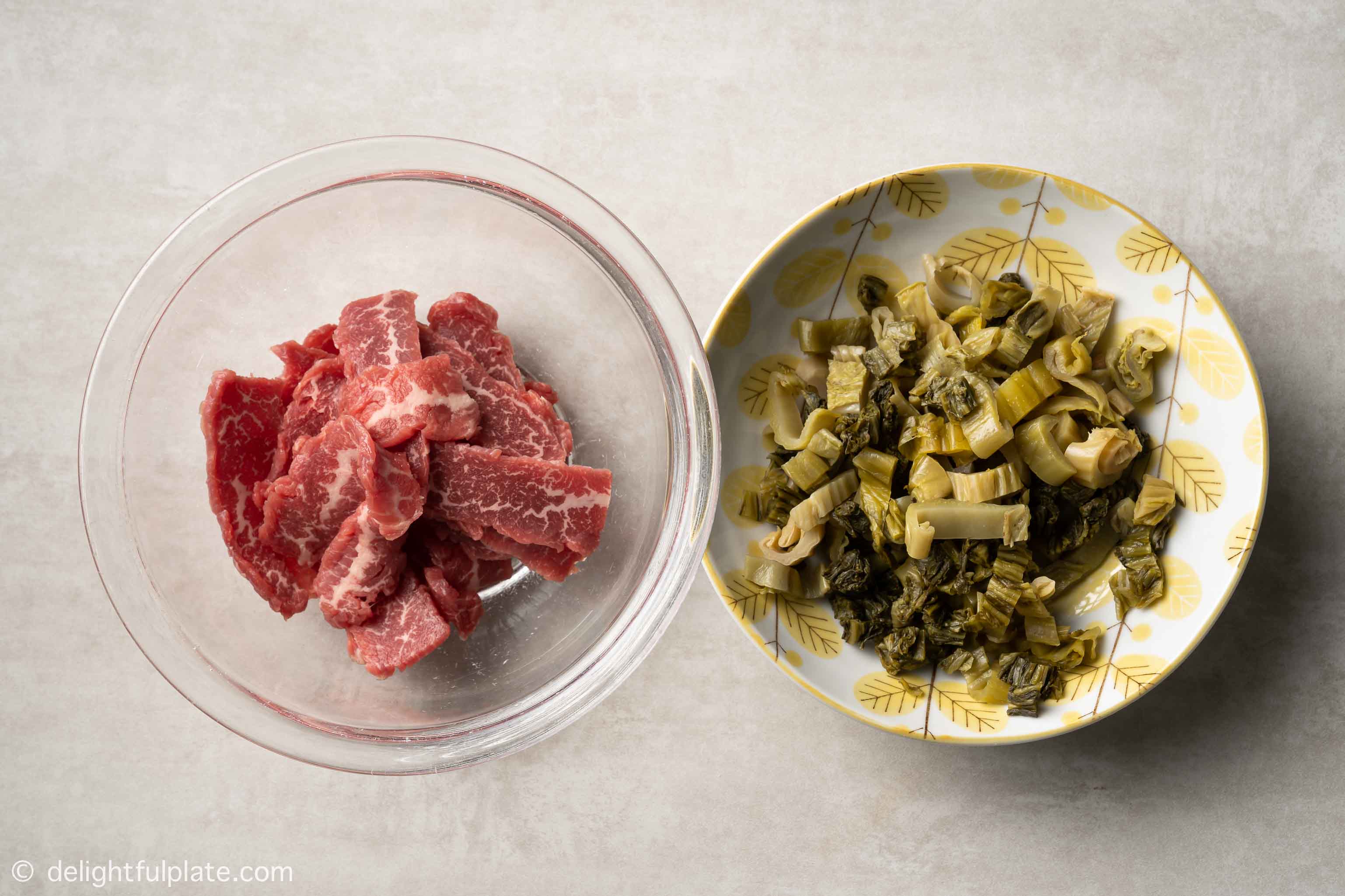 plates containing sliced beef and chopped mustard greens