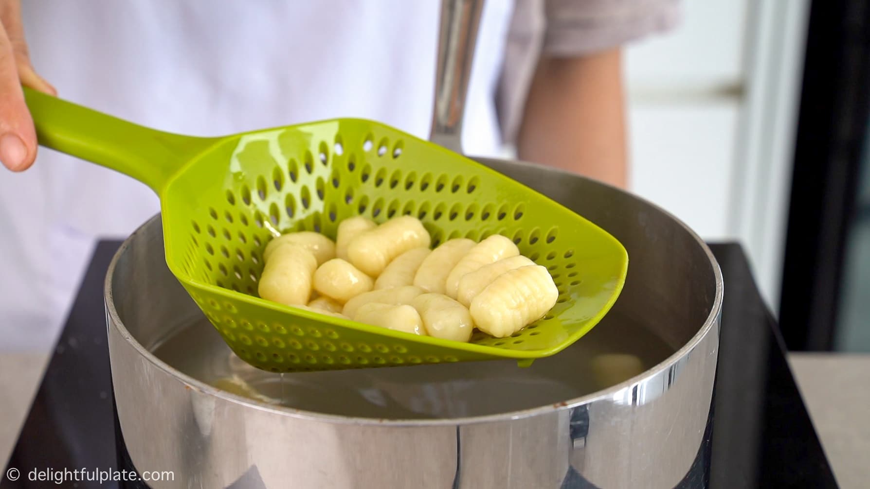 draining boiled gnocchi with a slotted spoon