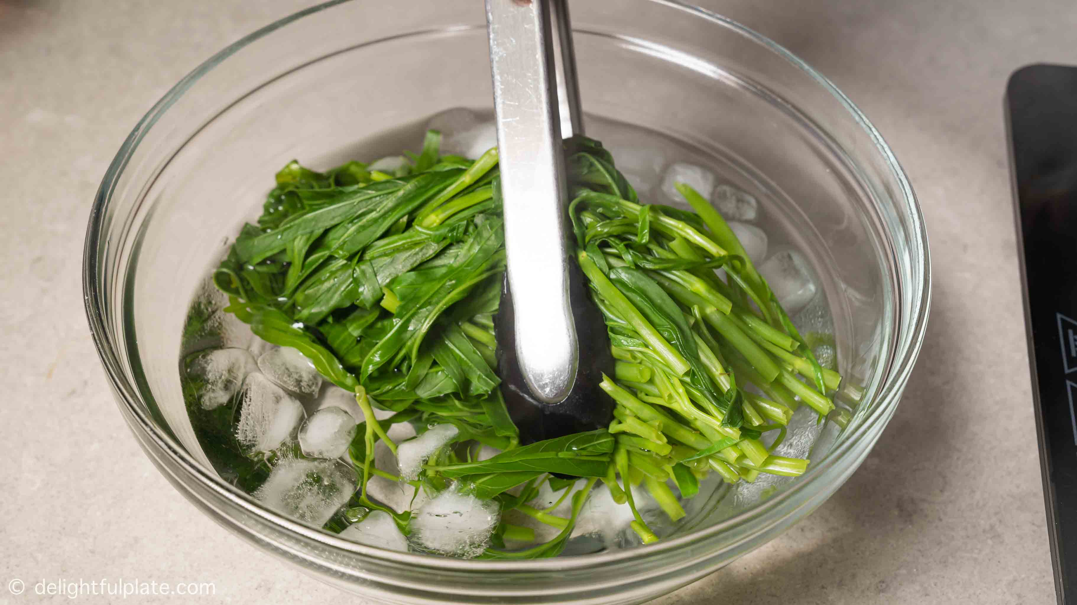 transferring blanched water spinach to iced cold water