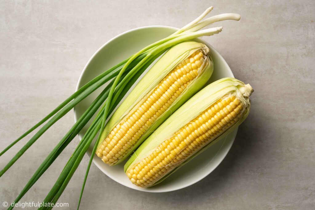 a plate with sweetcorn and scallion stalks