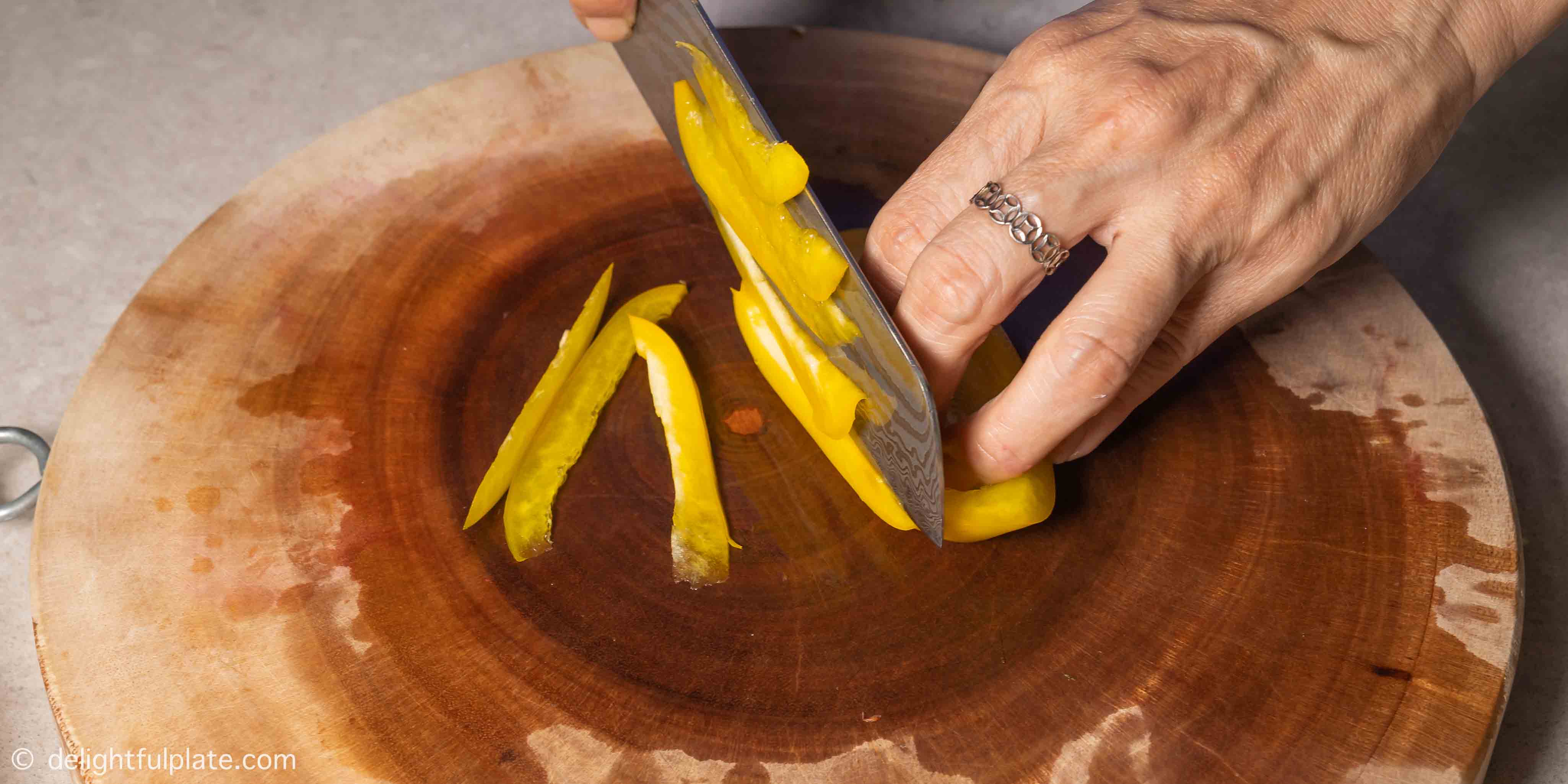 slicing yellow bell pepper into strips