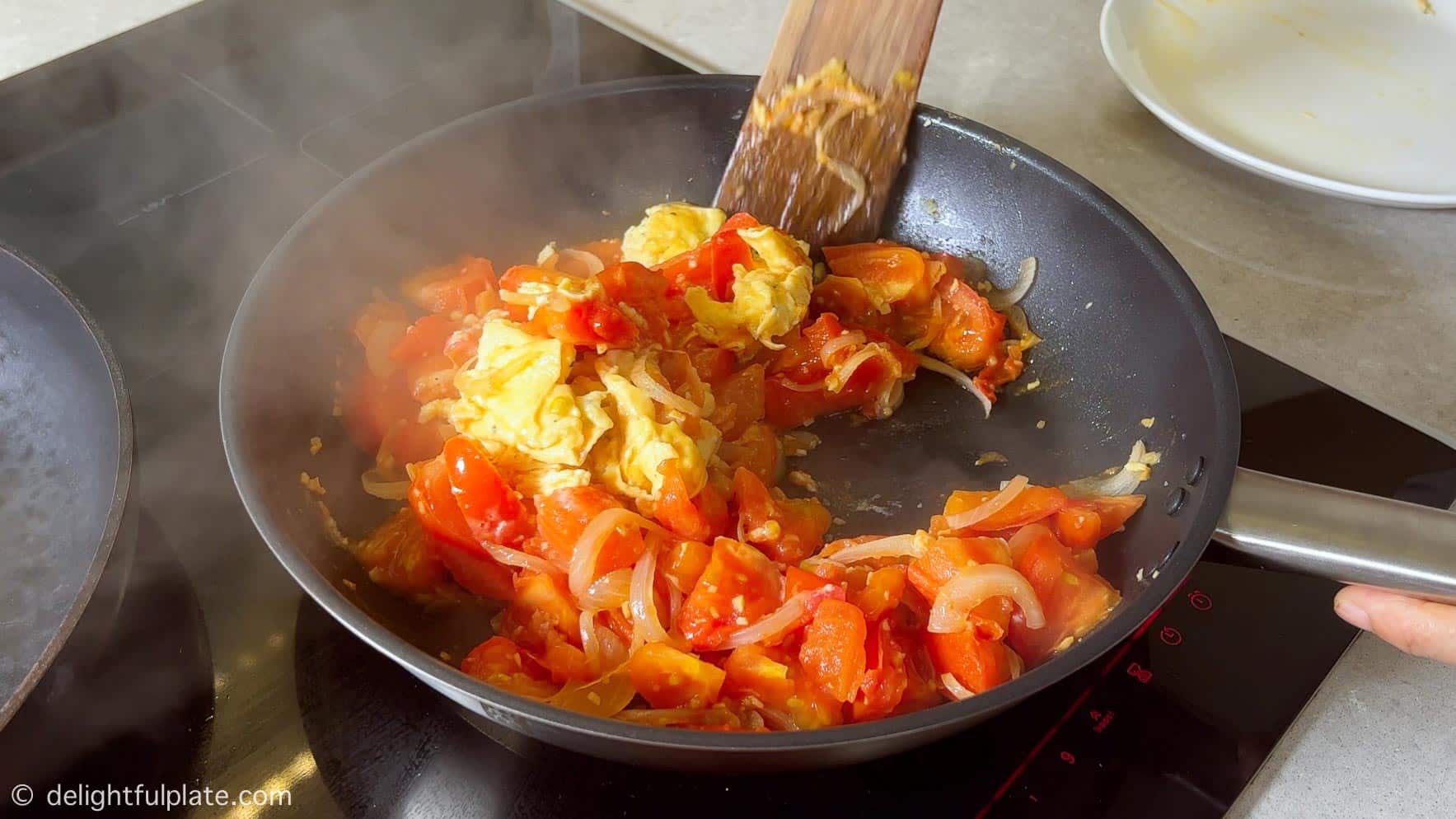 scramble eggs with tomatoes in a skillet