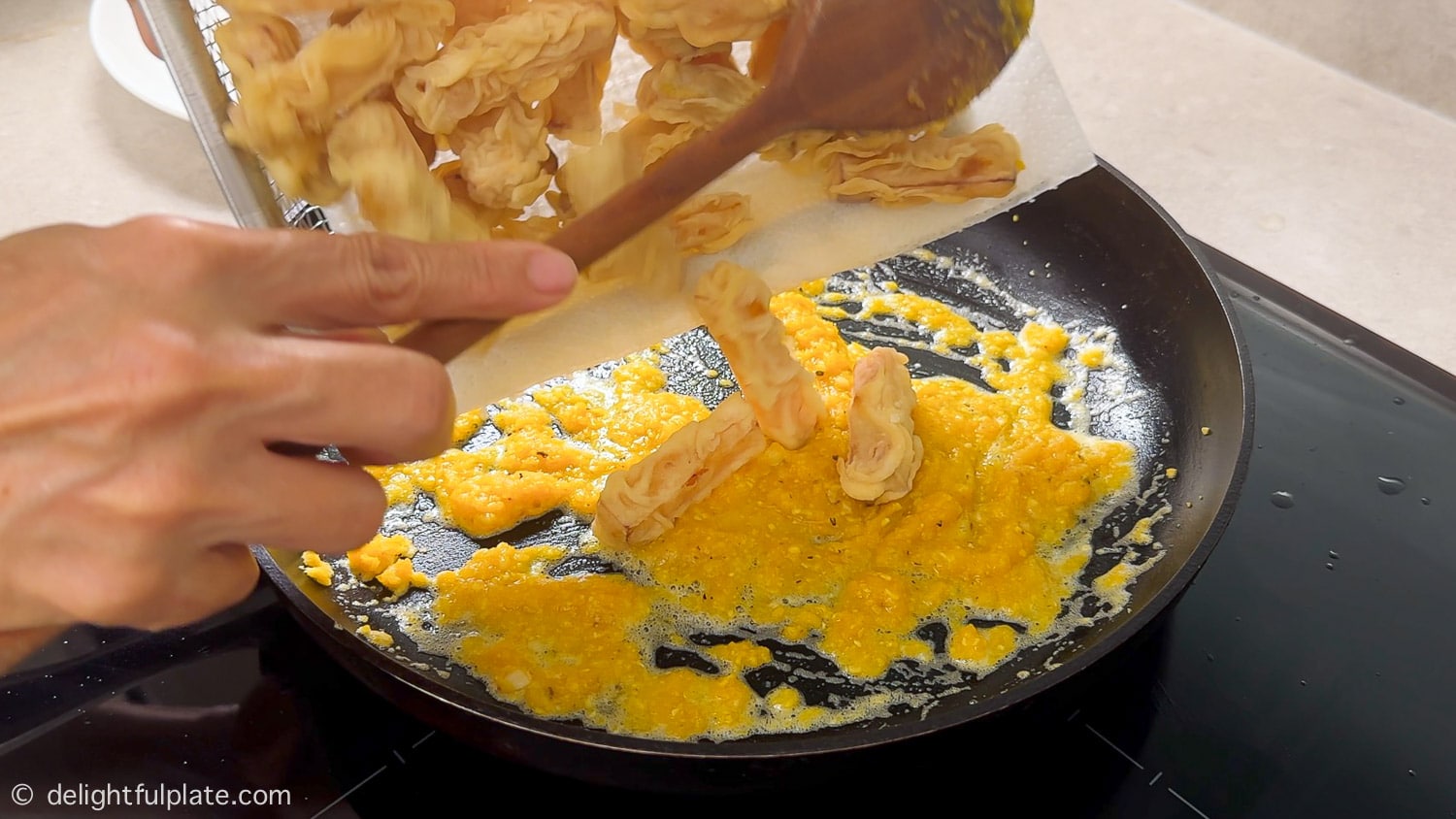 adding pumpkin to the pan of salted egg sauce