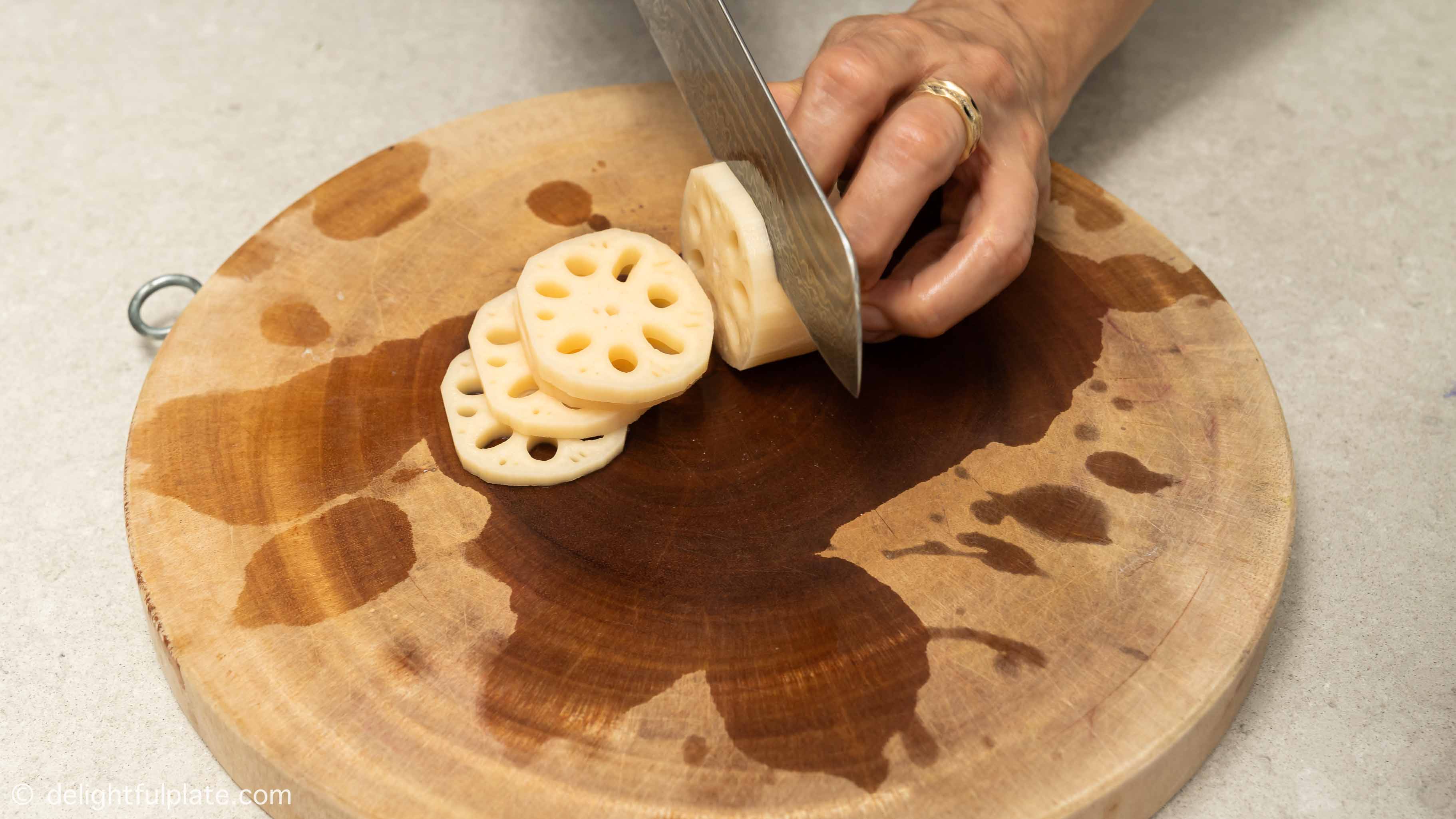 slicing lotus root on a cutting board