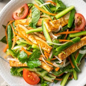 a plate of tofu salad with cucumber and tomato