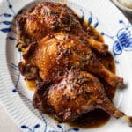 a plate of roasted duck legs with black pepper sauce