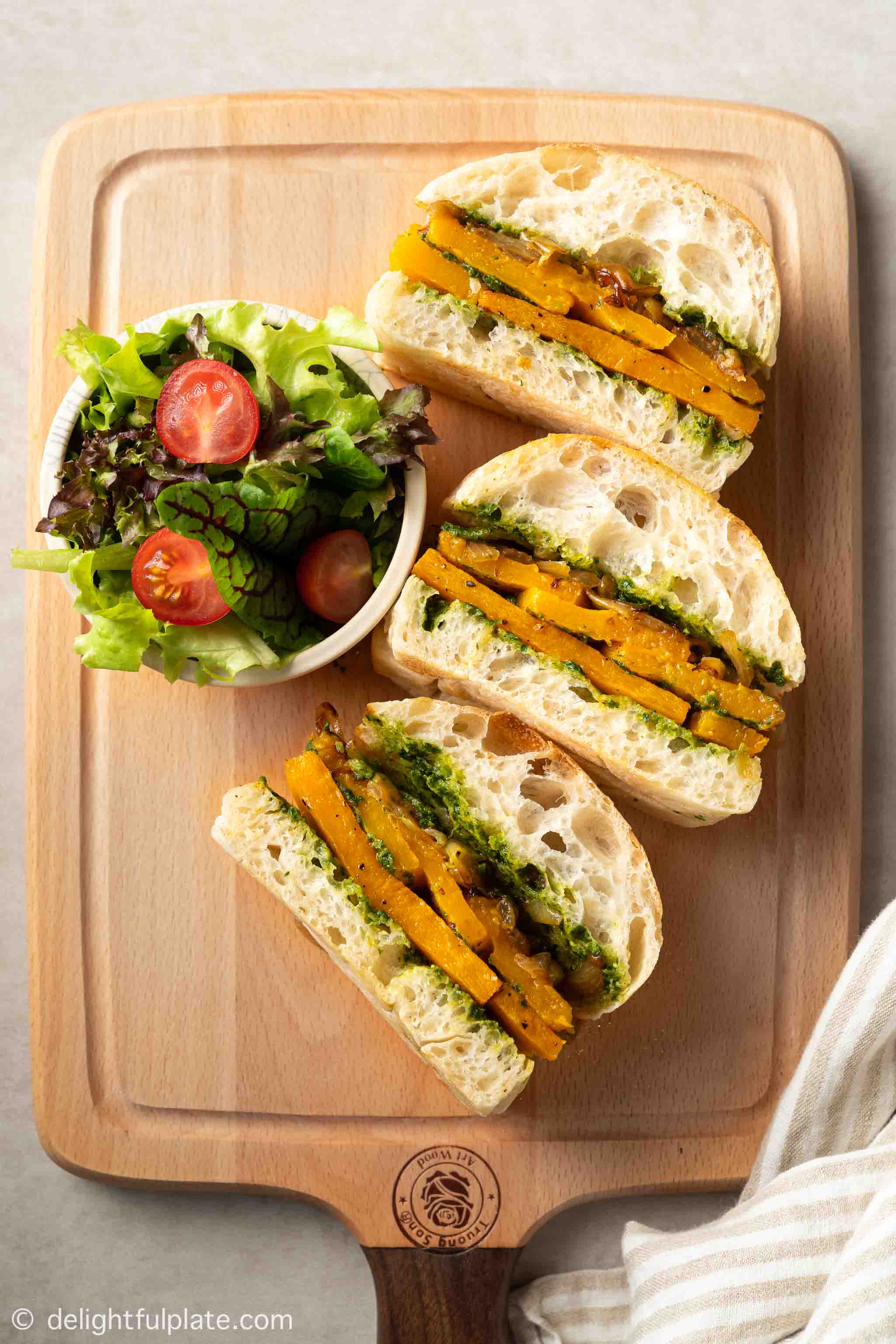 a tray of roasted butternut squash sandwiches with salad on the side