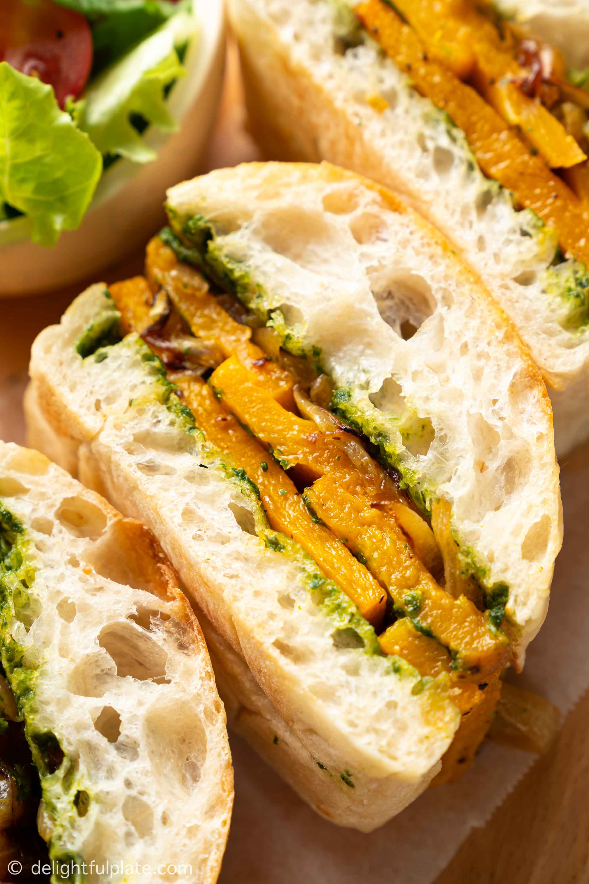 a slice of roasted butter squash sandwich with caramelized onions and pesto