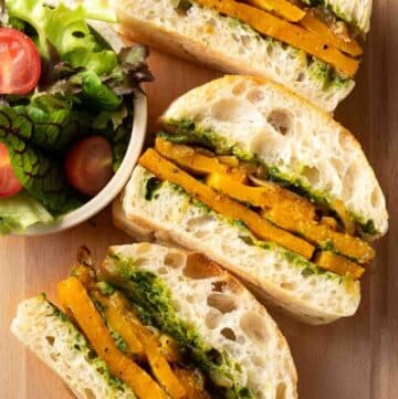 a tray of roasted butternut squash sandwiches with salad on the side