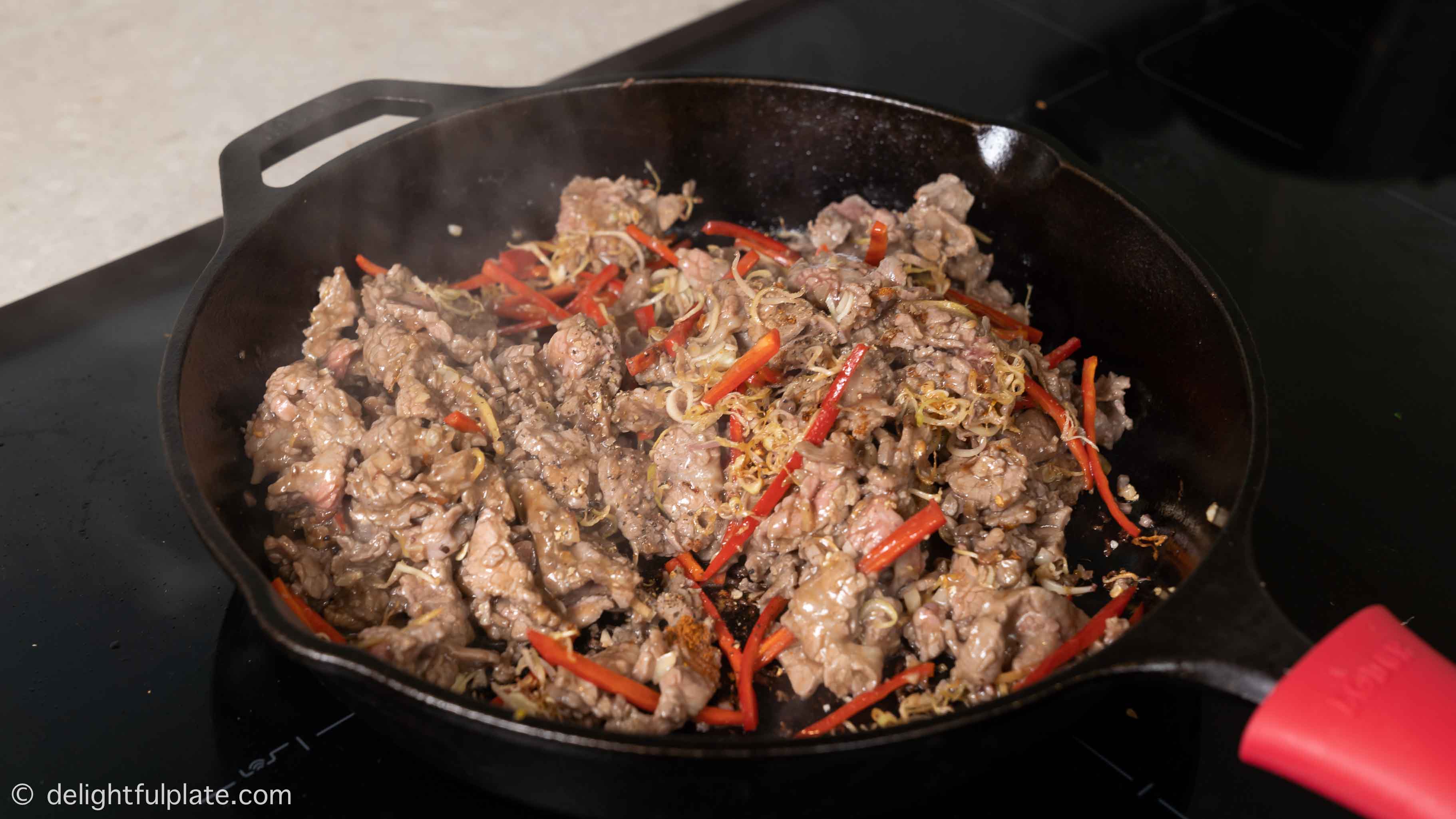 a skillet of stir-fried beef with lemongrass on the stovetop