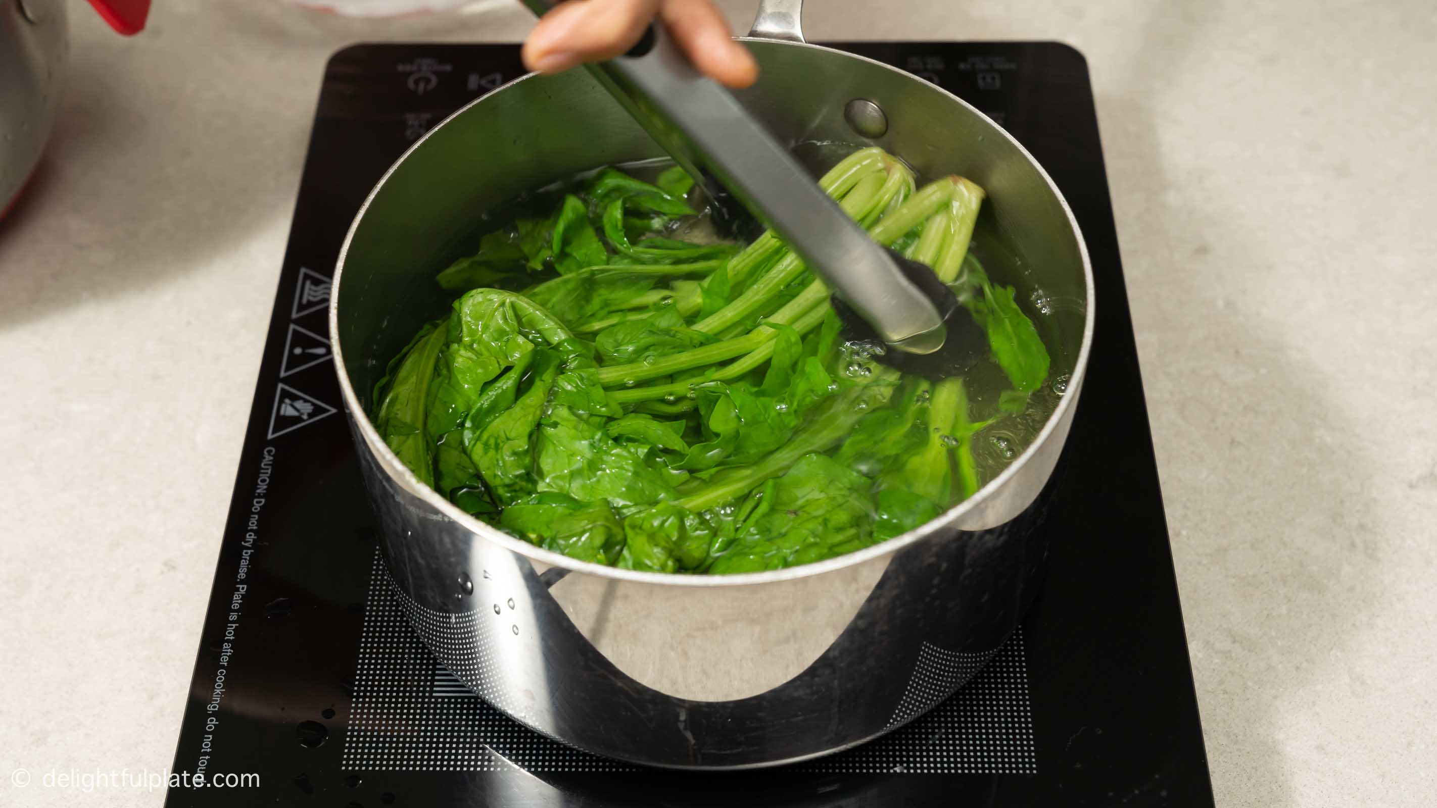 blanching spinach in a large pot of water.