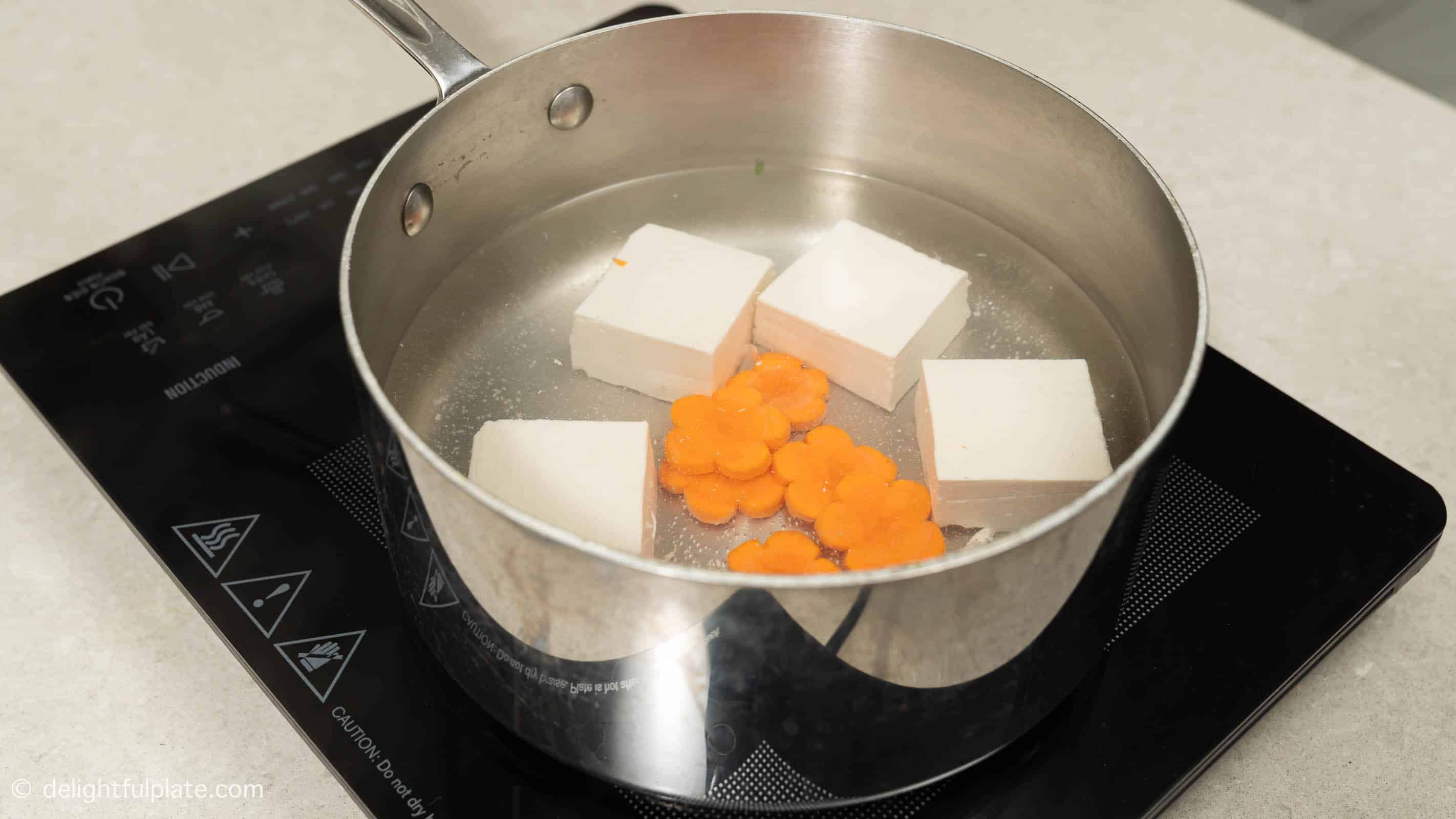 Blanching tofu and carrot in a large pot of water.