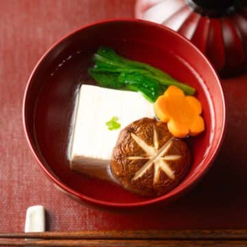 a lacquer bowl with Japanese suimono clear soup with tofu, mushroom and vegetables.