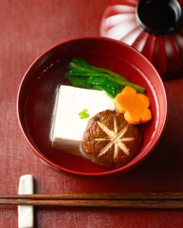 a lacquer bowl with Japanese suimono clear soup with tofu, mushroom and vegetables.