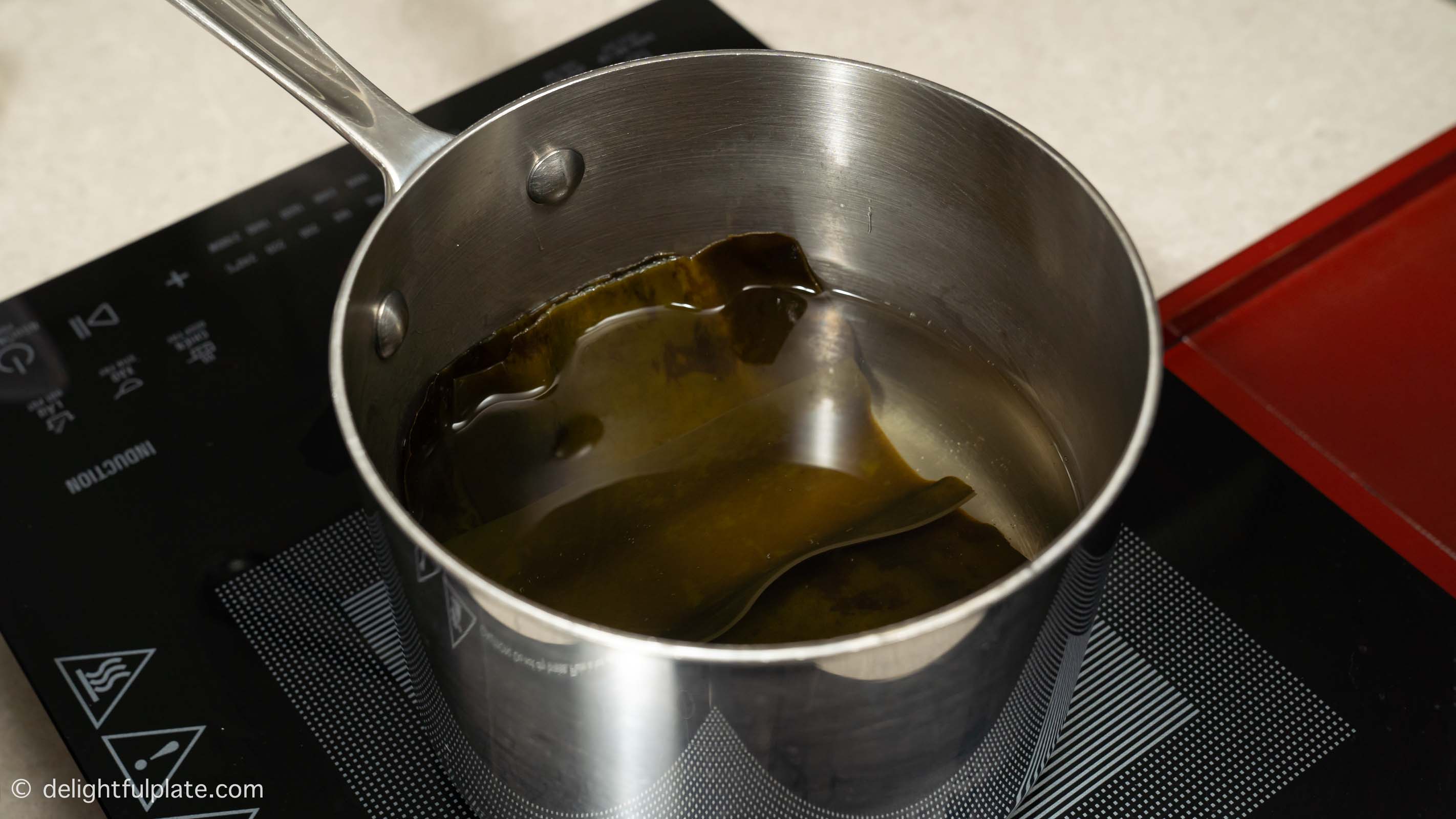 heating dried kelp and water in a pot to make kombu dashi.