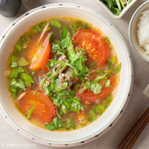a bowl of canh bo rau ram (Vietnamese tomato beef soup).