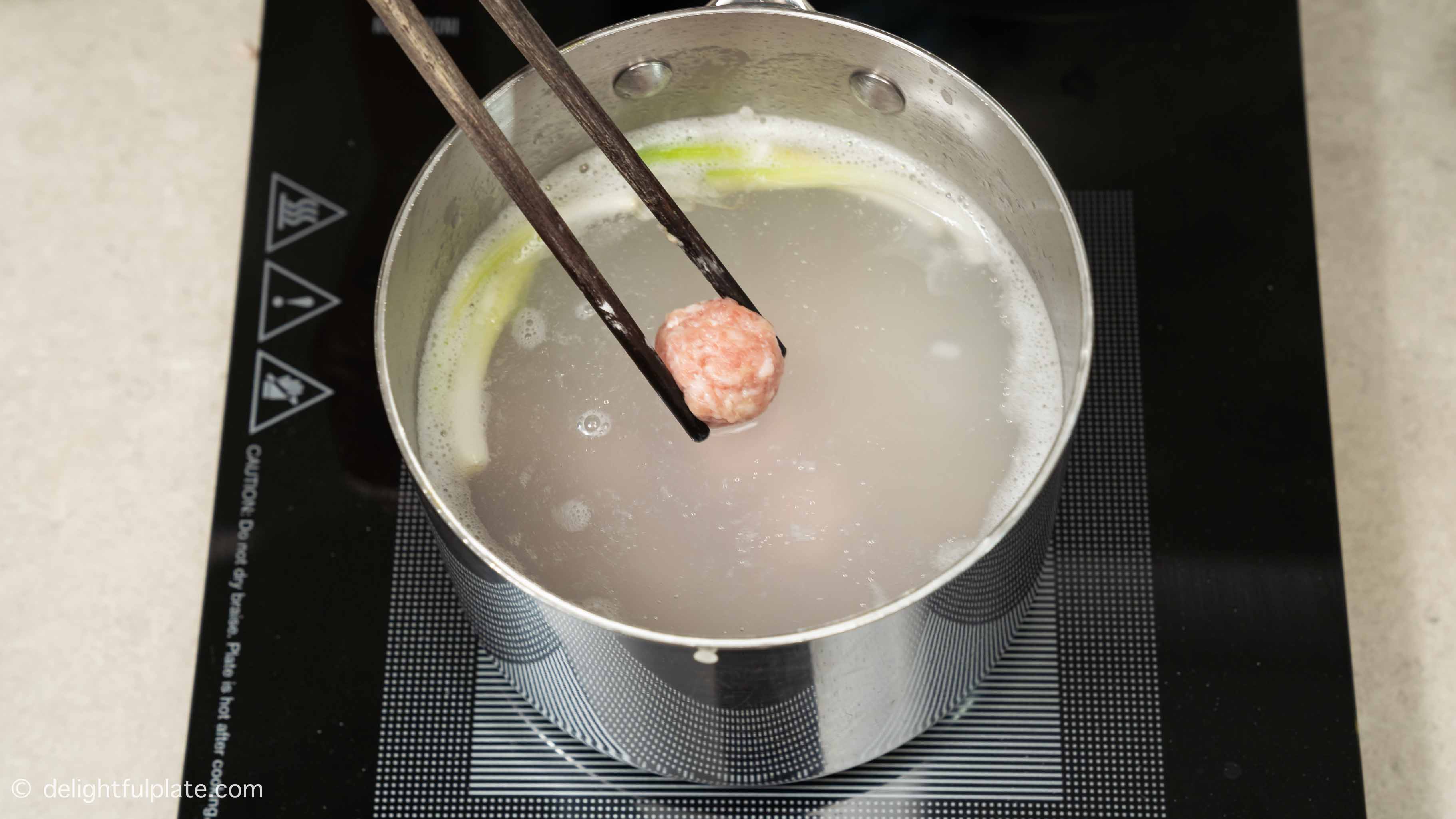 adding meatballs to the congee pot.