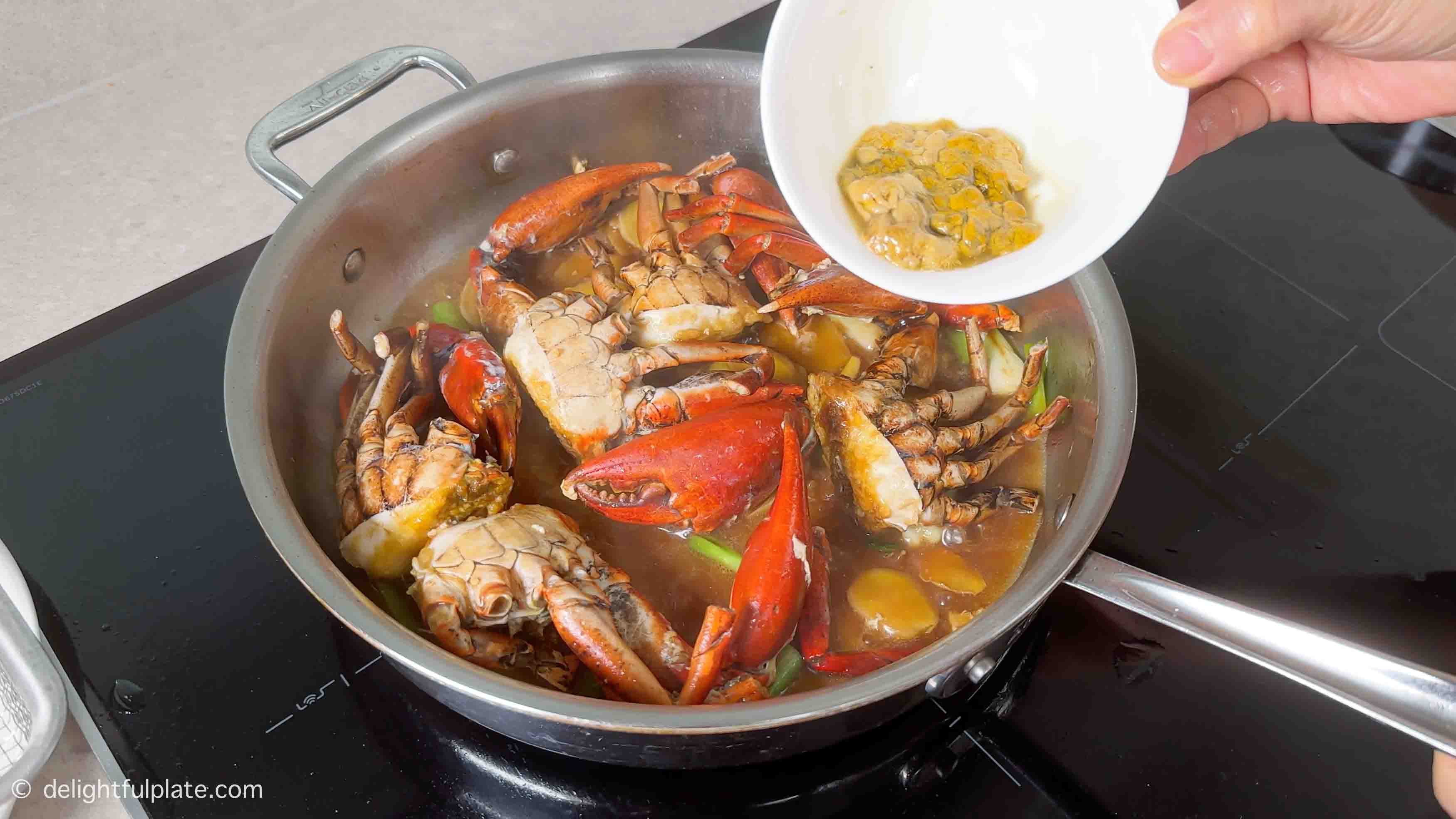 adding seasonings into the skillet to stir-fry with the crabs.