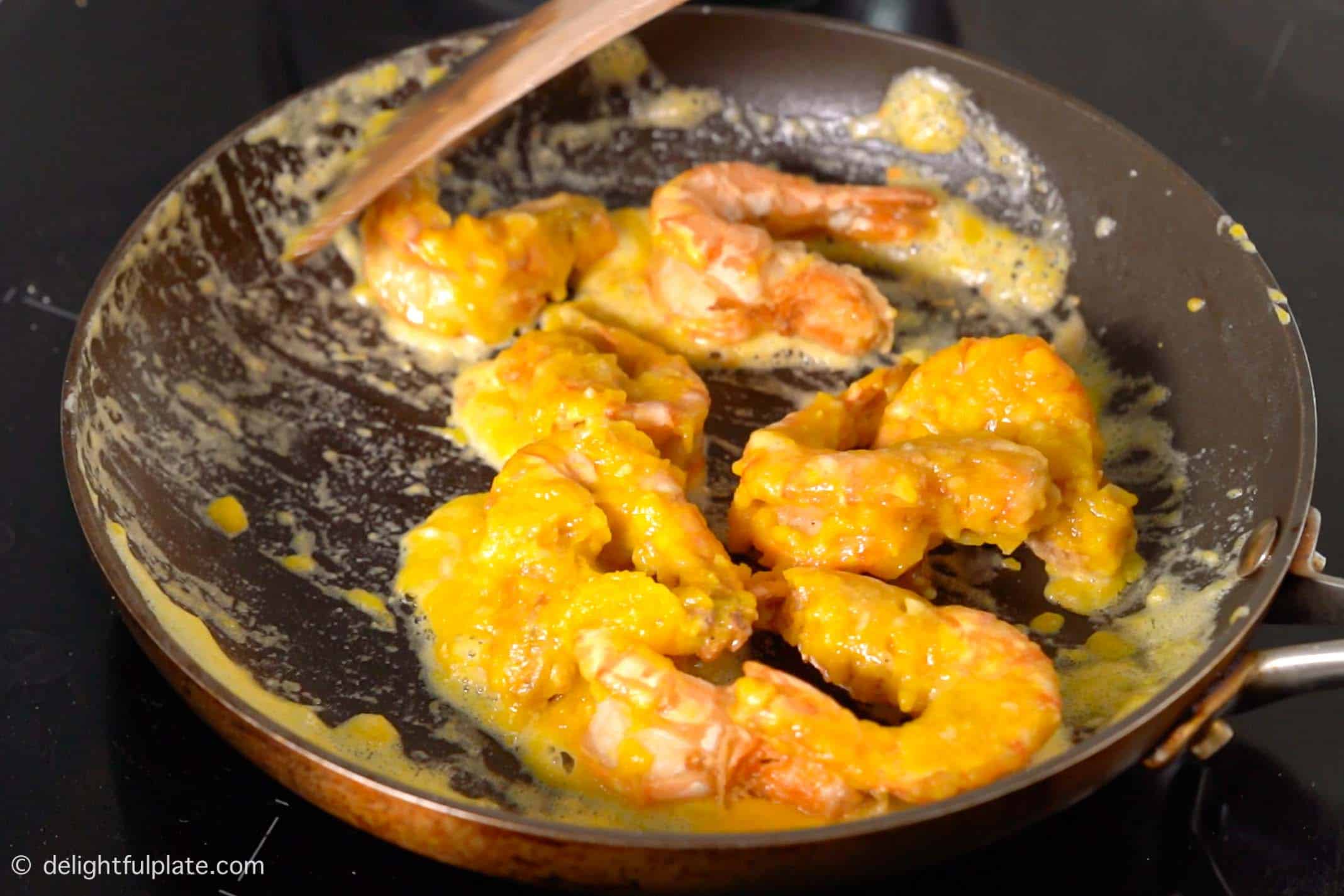 coating the shrimp with the salted egg sauce.